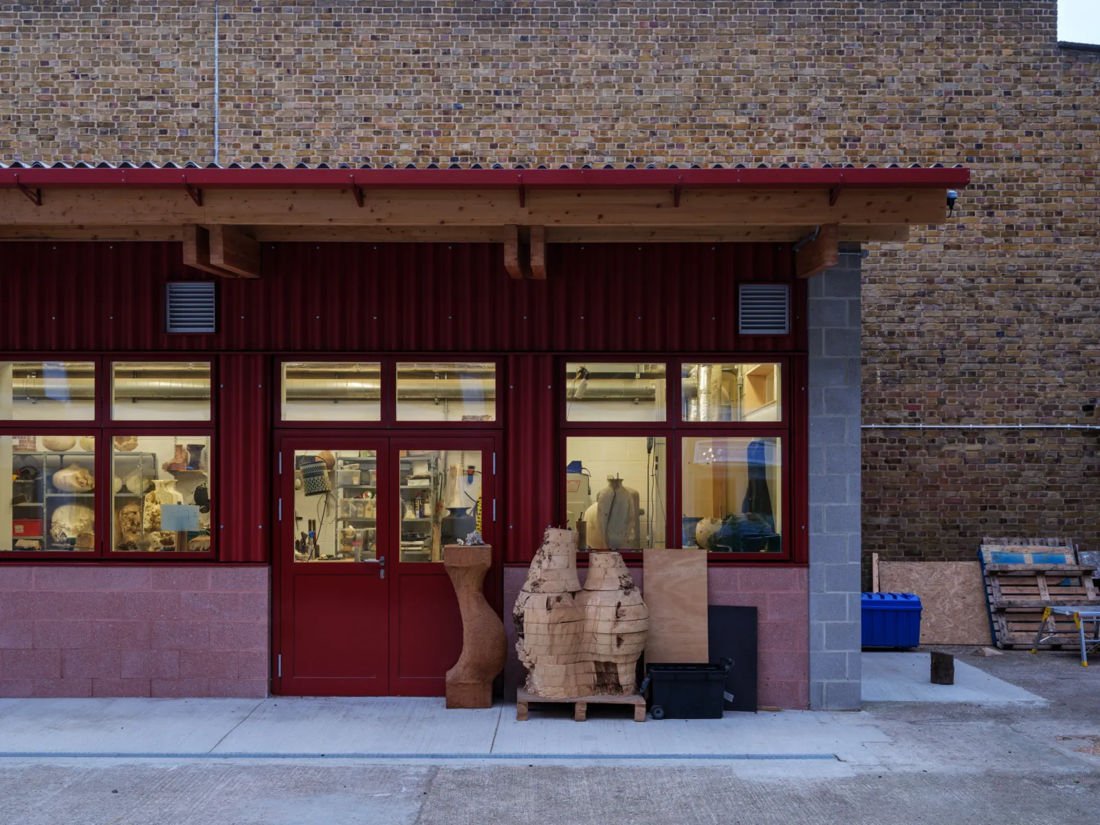wooden sculptures in front of a red facade