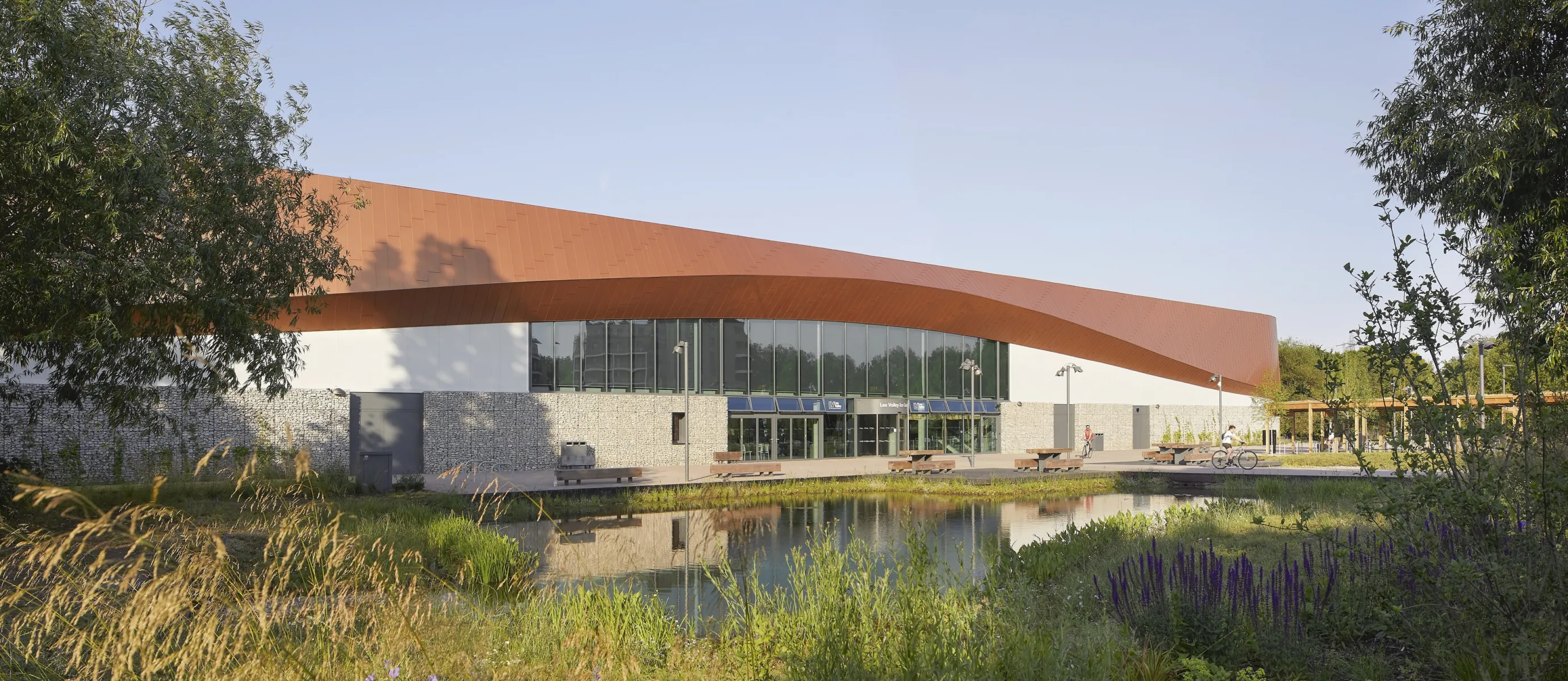 large rust coloured sloping and curving roof on a modern building