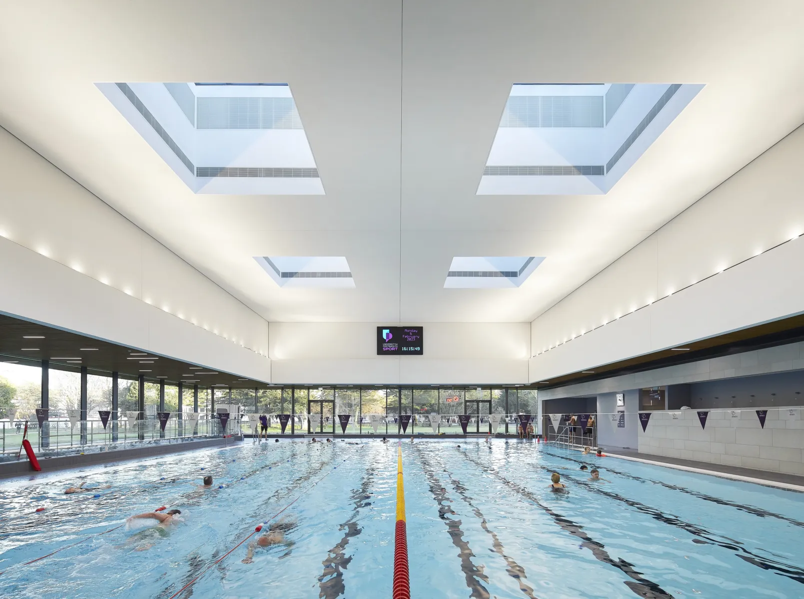 The image shows a swimming pool and in a large room with skylights