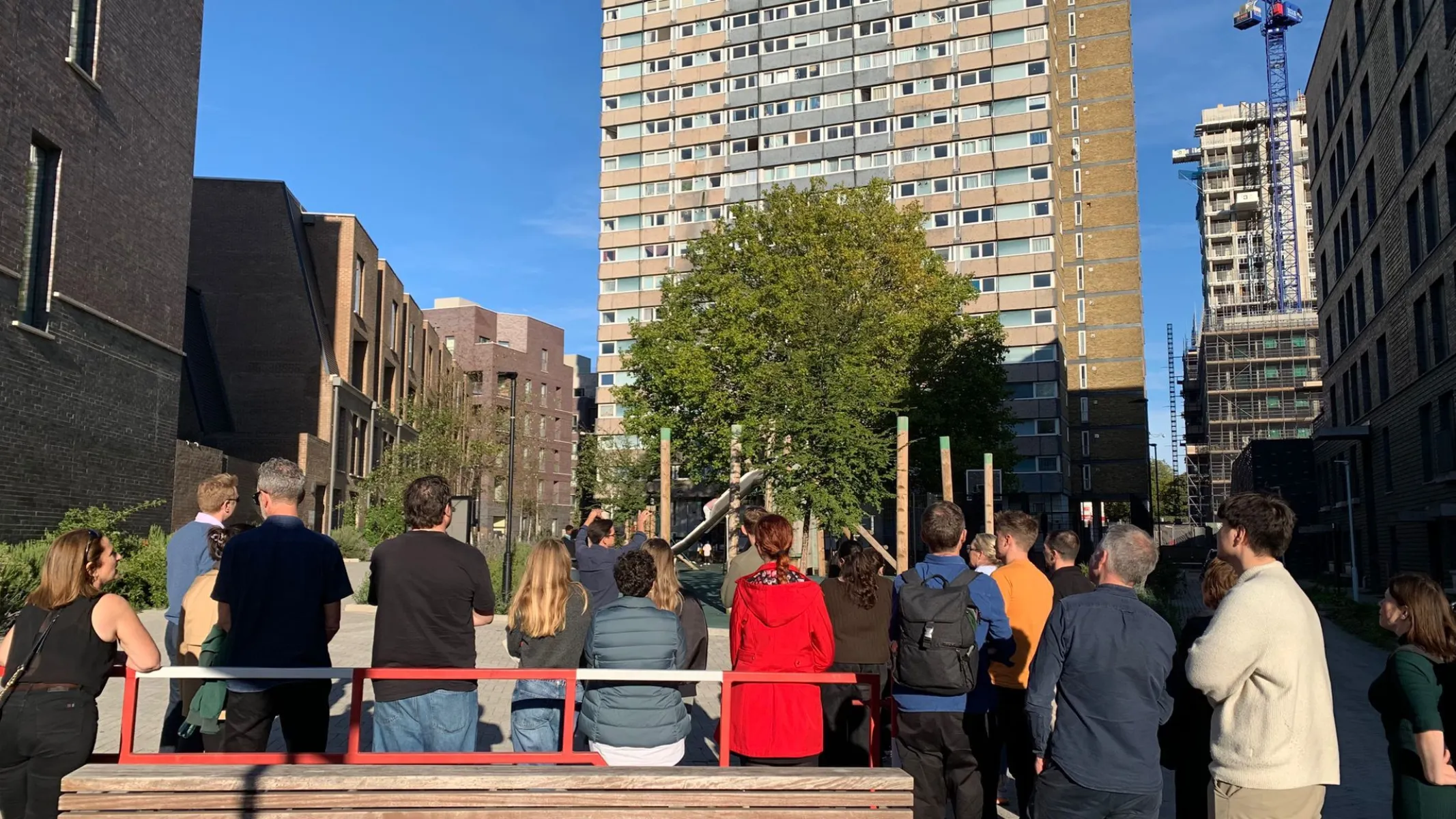people standing in front of a tower block with brick housing on both sides