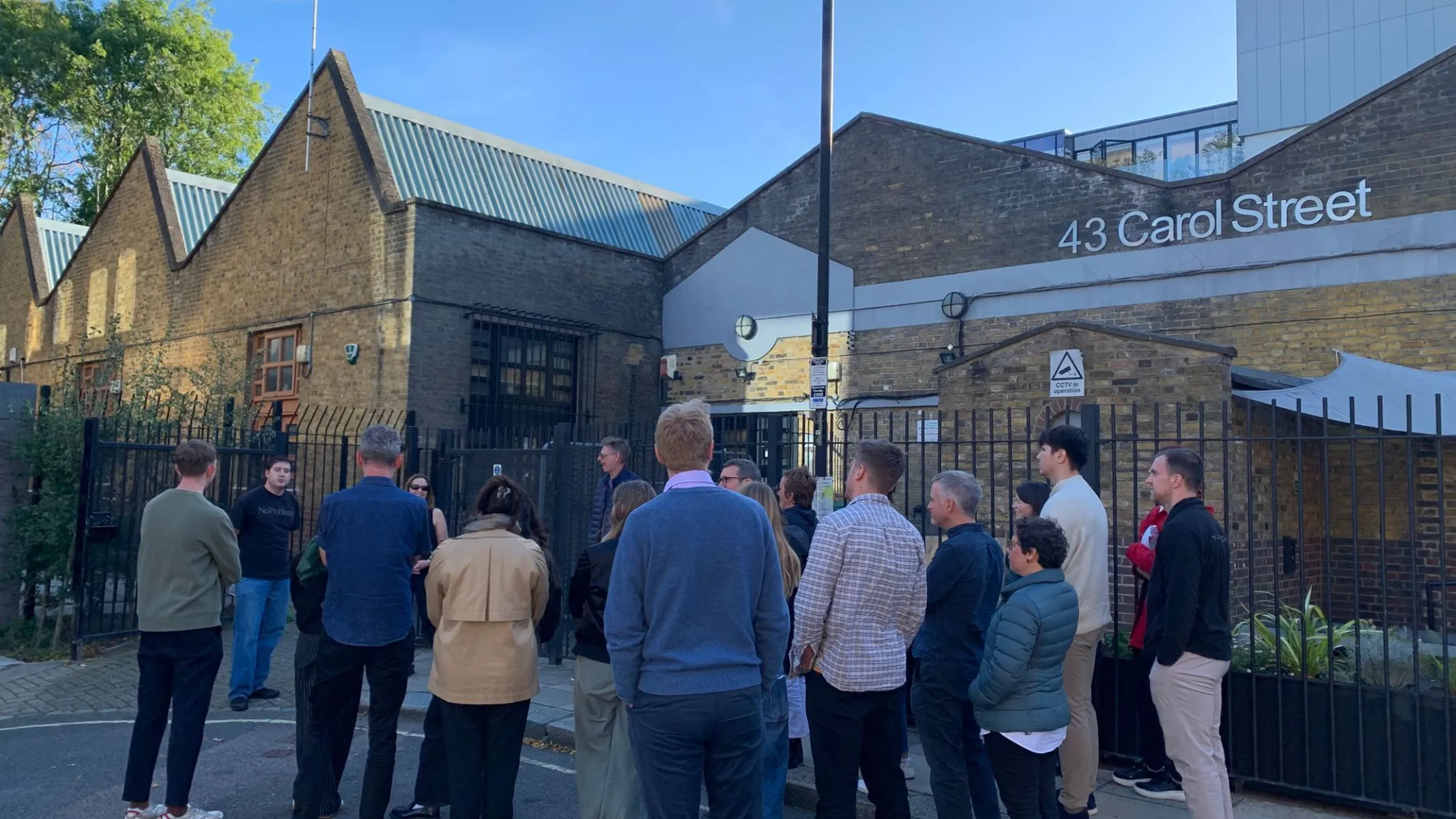 people standing in front of a brick building with a sign that says 43 Carol Street