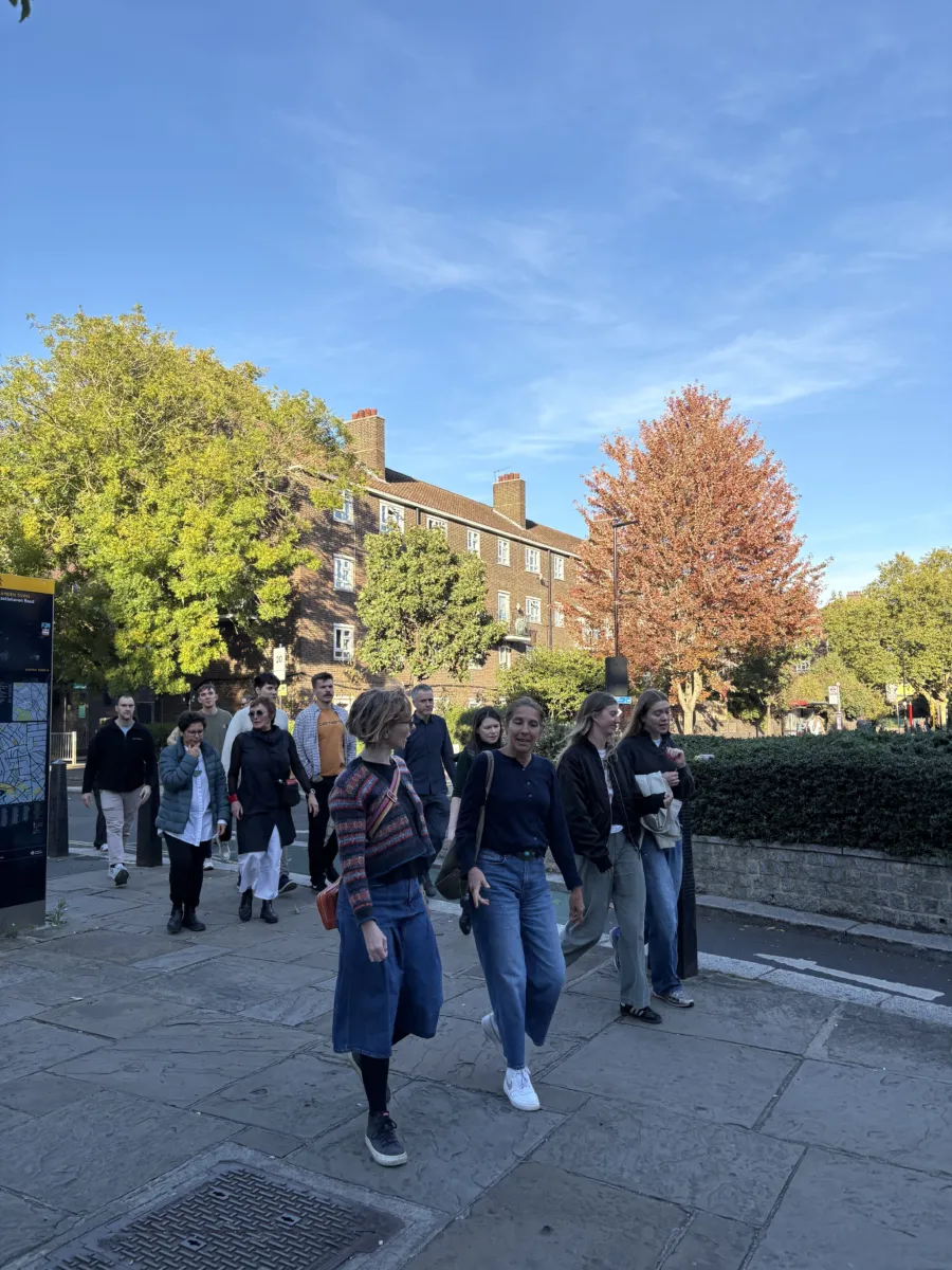 people walking along stone paving with trees in the background.