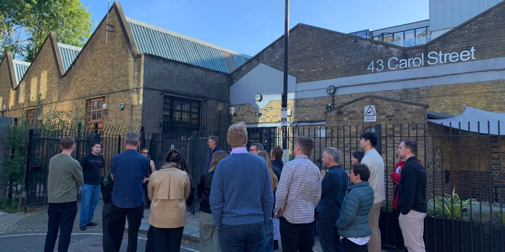people standing in front of a brick building with a sign that says 43 Carol Street