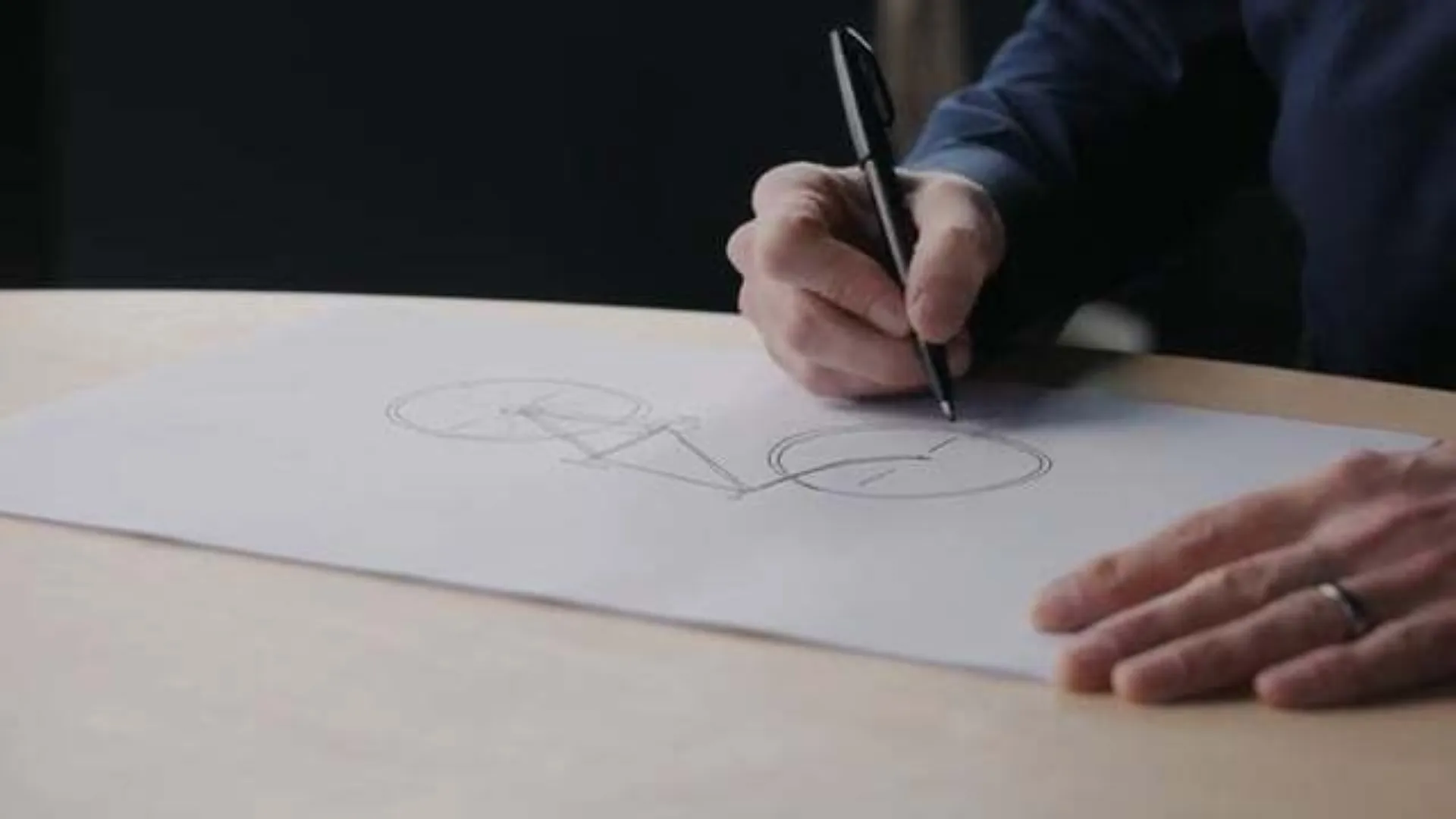 a person drawing a bicycle on a sheet of paper