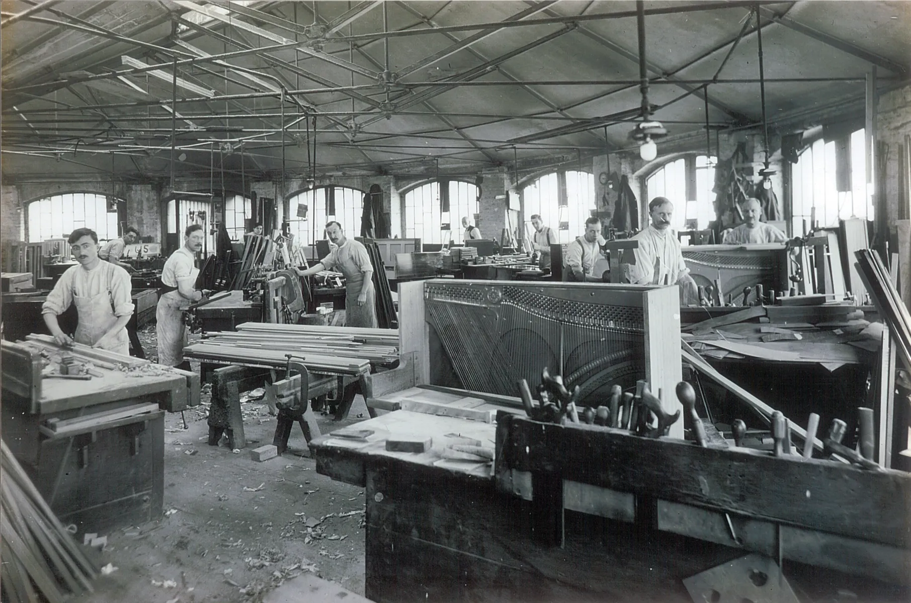Black and white images shows men working on pianos