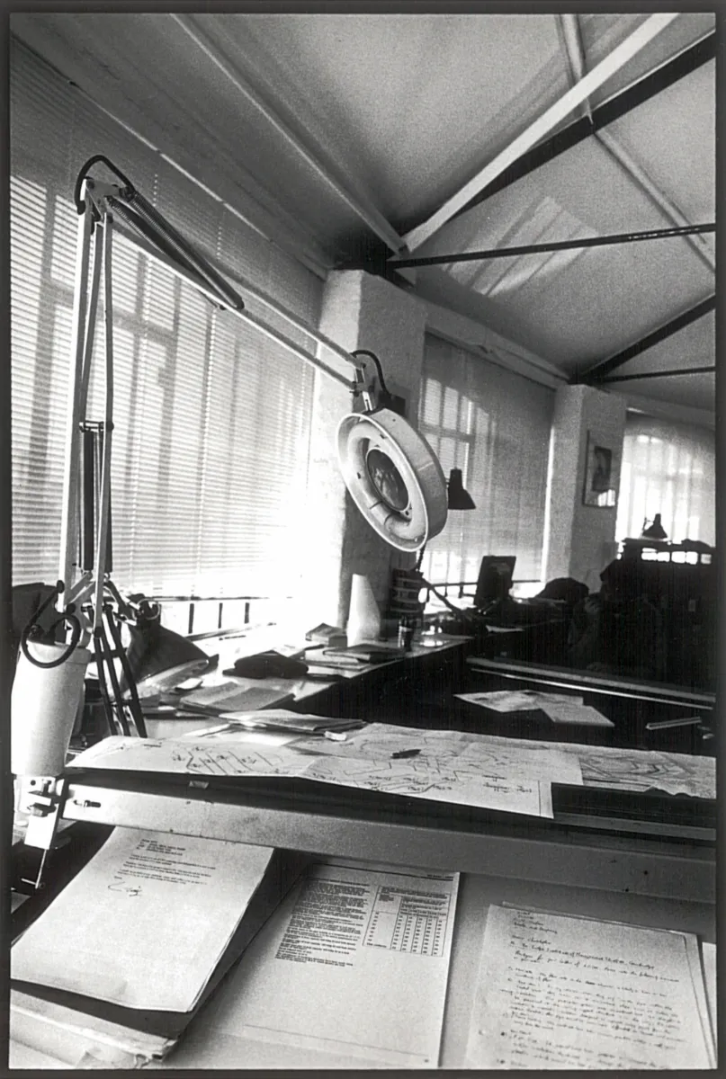 black and white image shows a lamp on a desk with papers