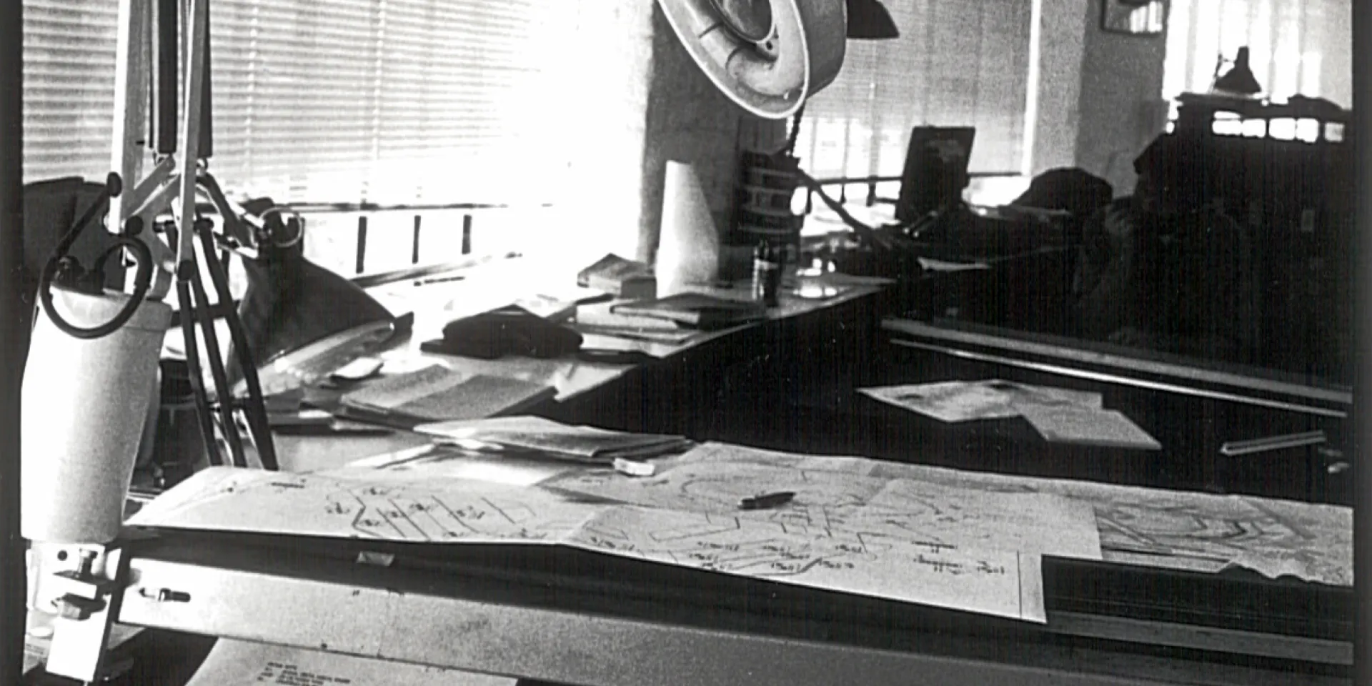 black and white image shows a lamp on a desk with papers
