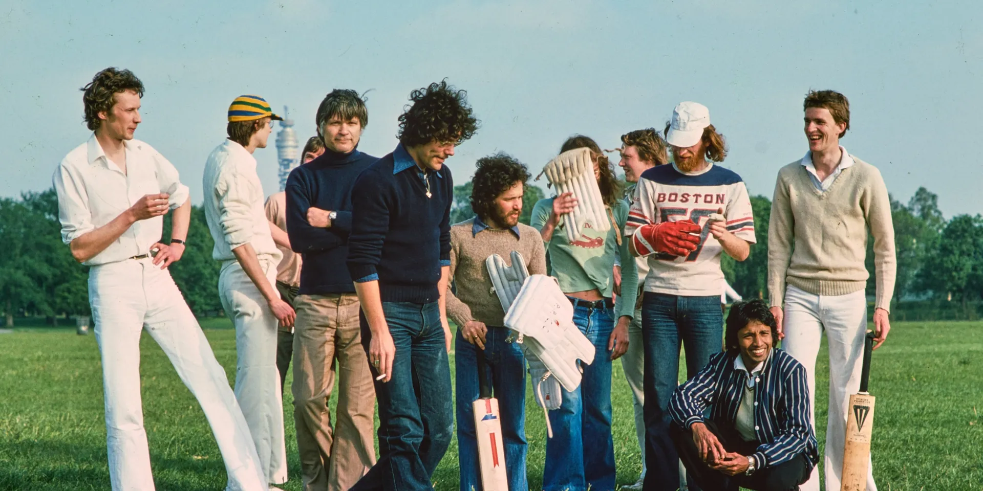 Men standing on grass in Regent's Park with cricket bats