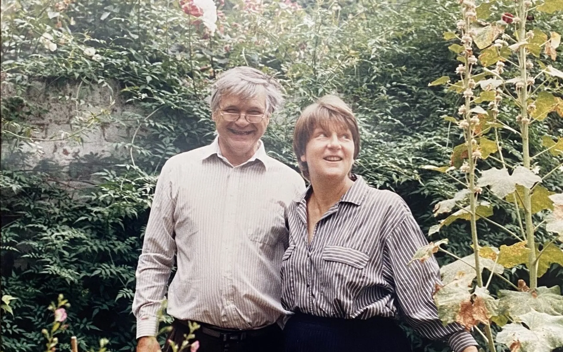 1980s colour photograph of Max and his wife Taddy in their garden, standing together and smiling at the camera.