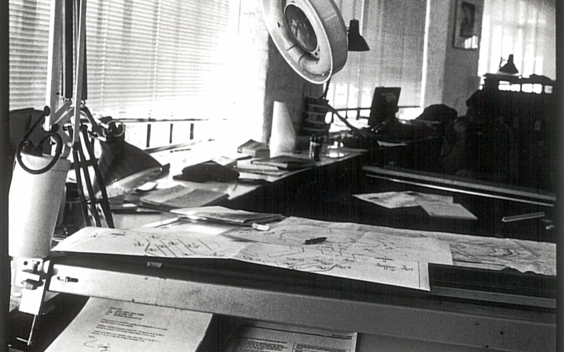 black and white image shows a lamp on a desk with papers