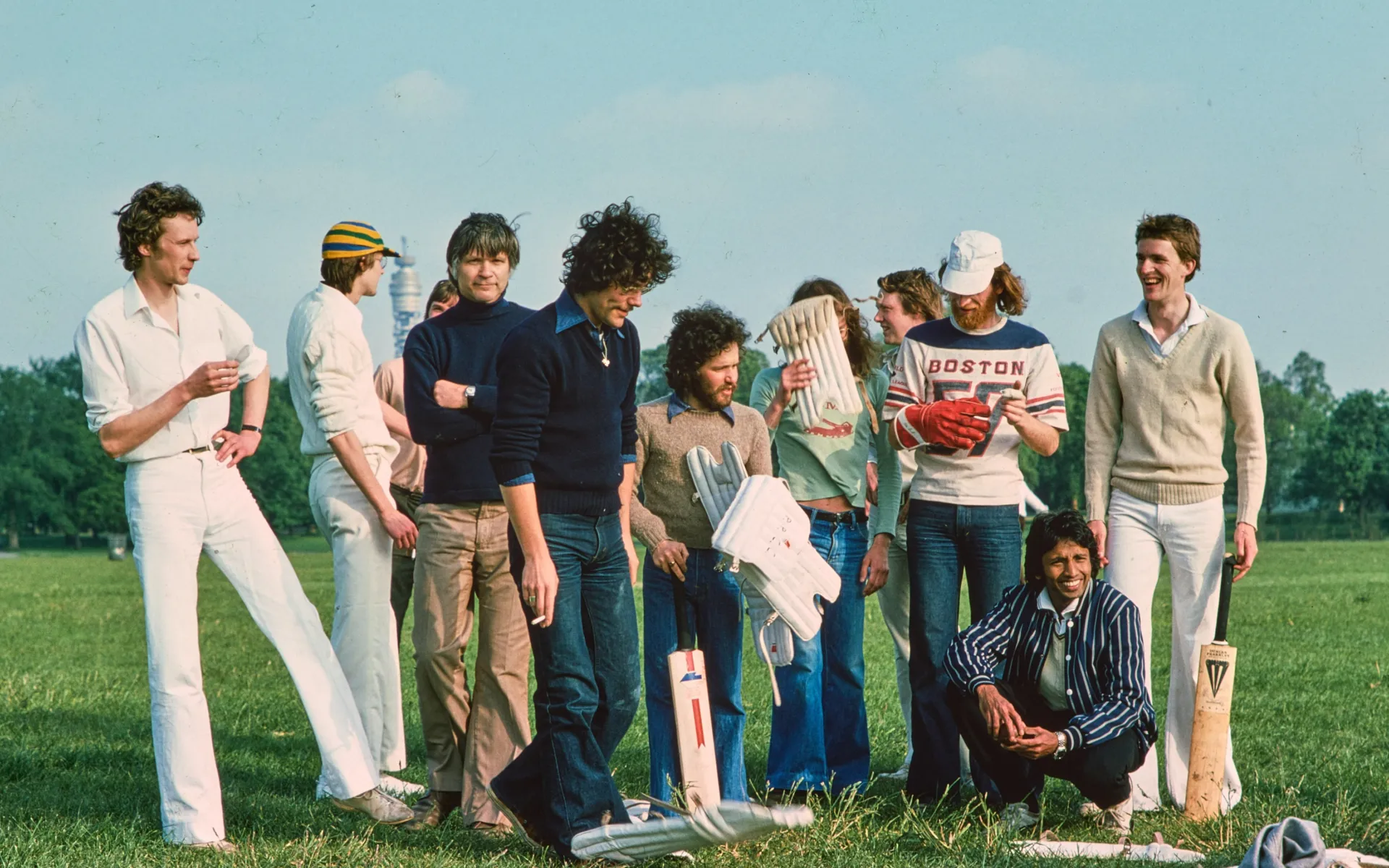 Men standing on grass in Regent's Park with cricket bats