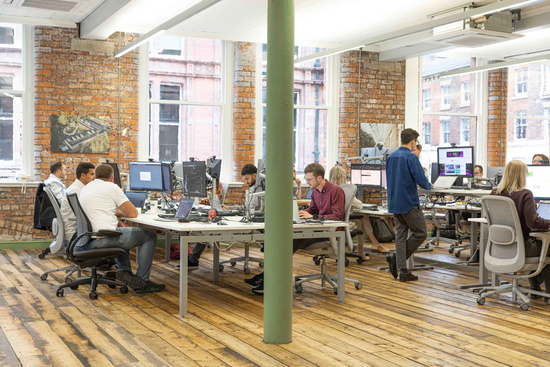 Wide shot of people working at adjustable height desks in our Manchester office.