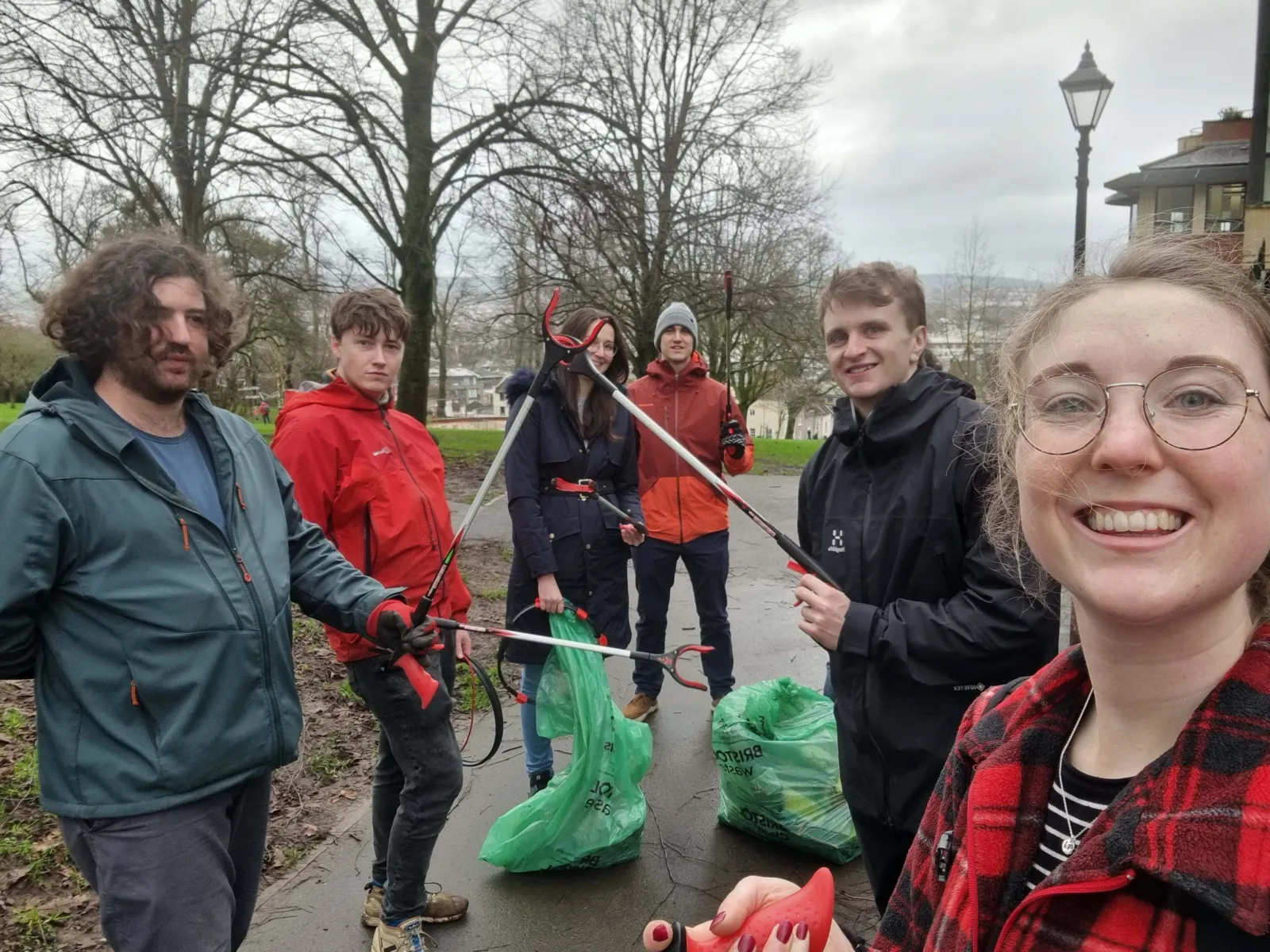 Six people looking at the camera with litter pickers and bin bags on their hands