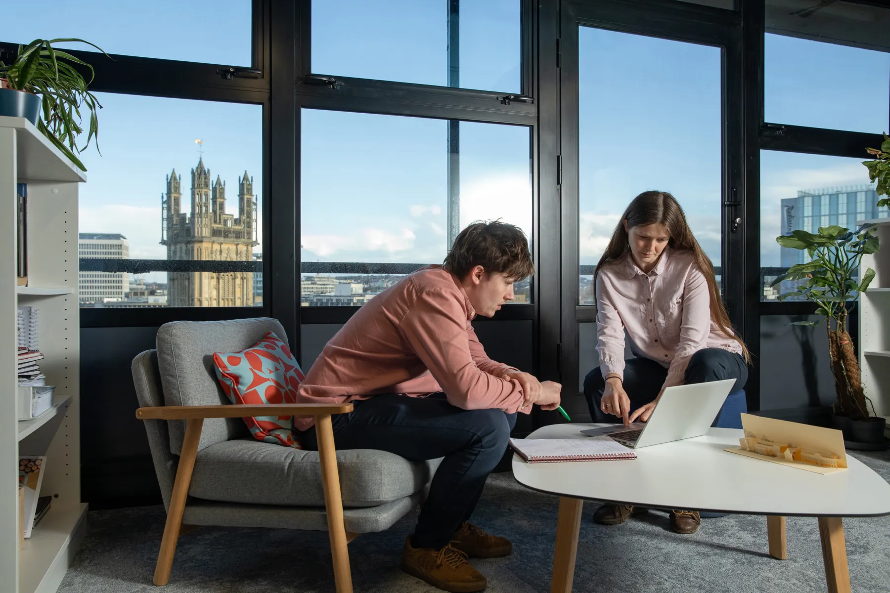 Two people sitting in comfortable chairs, looking at a laptop
