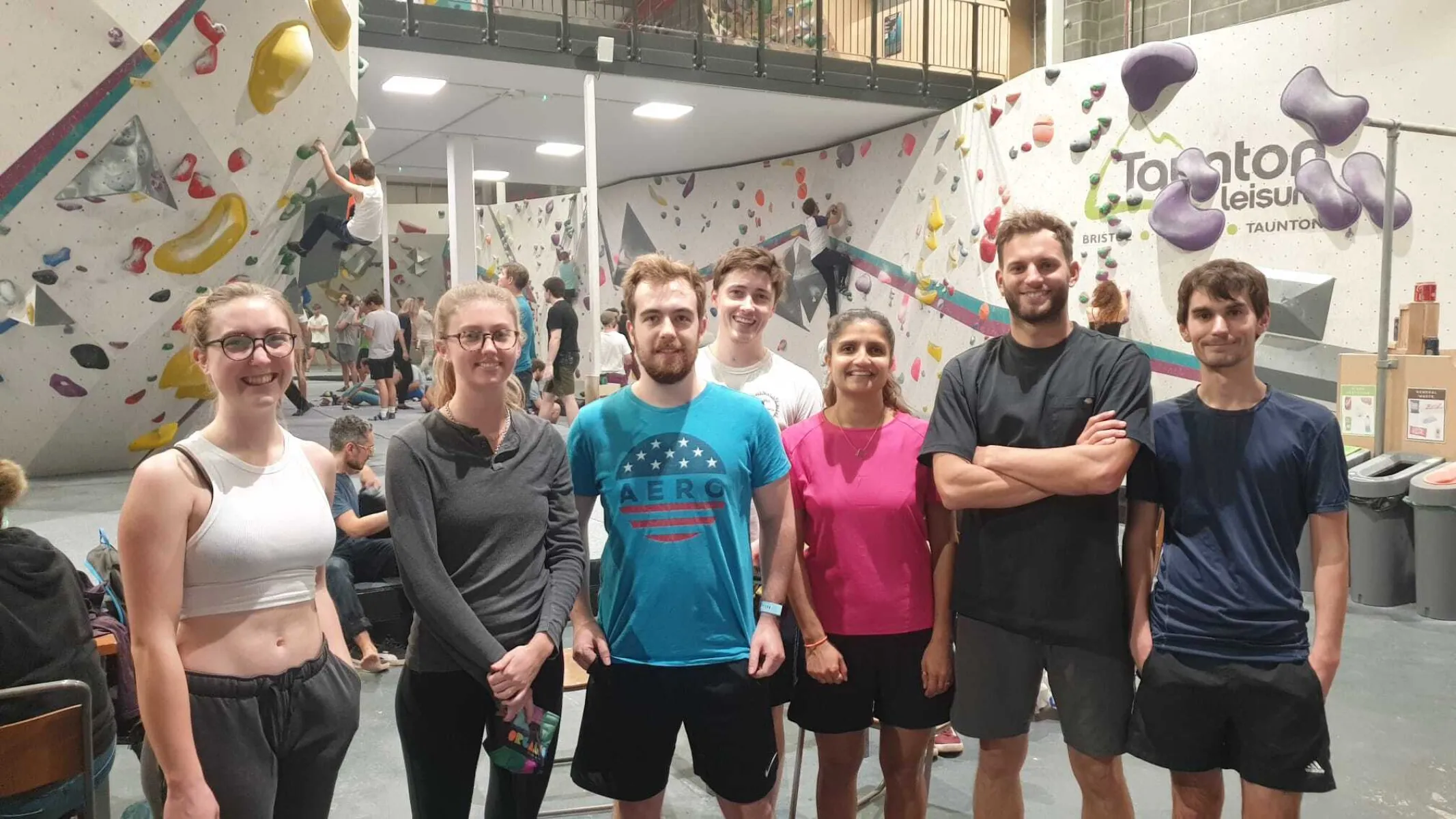 Seven people standing inside a bouldering centre