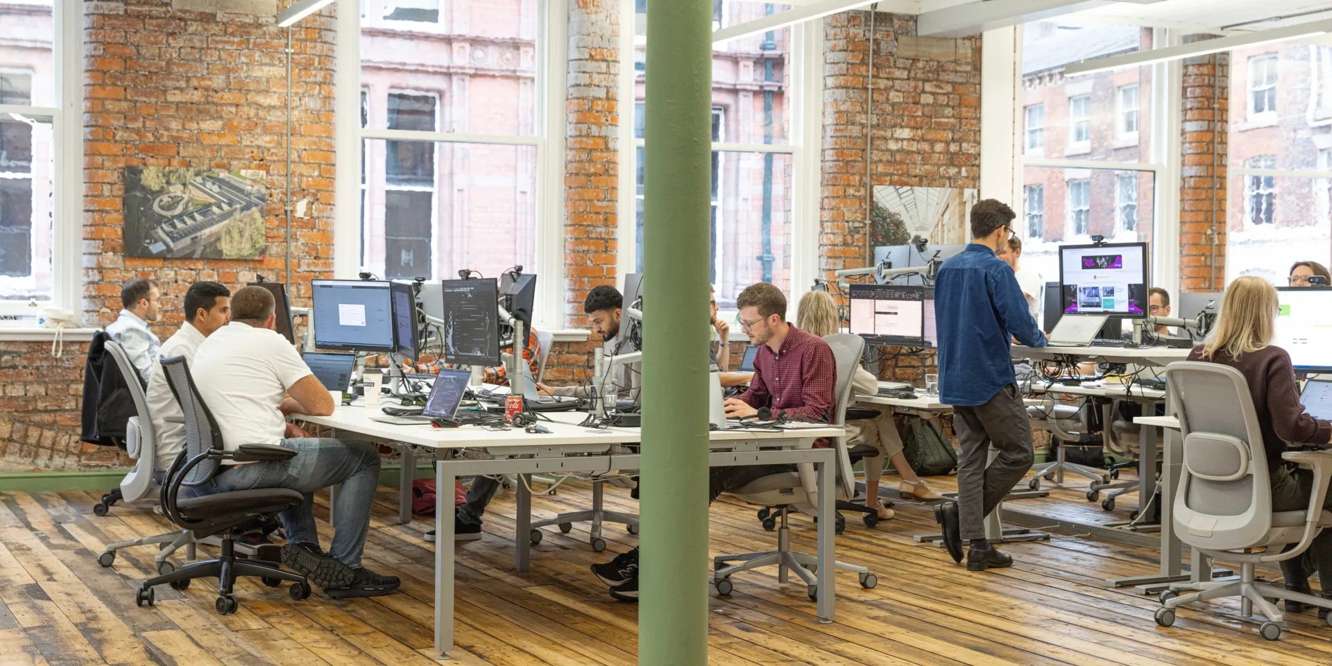 People working at desks in an open plan office with wooden floors