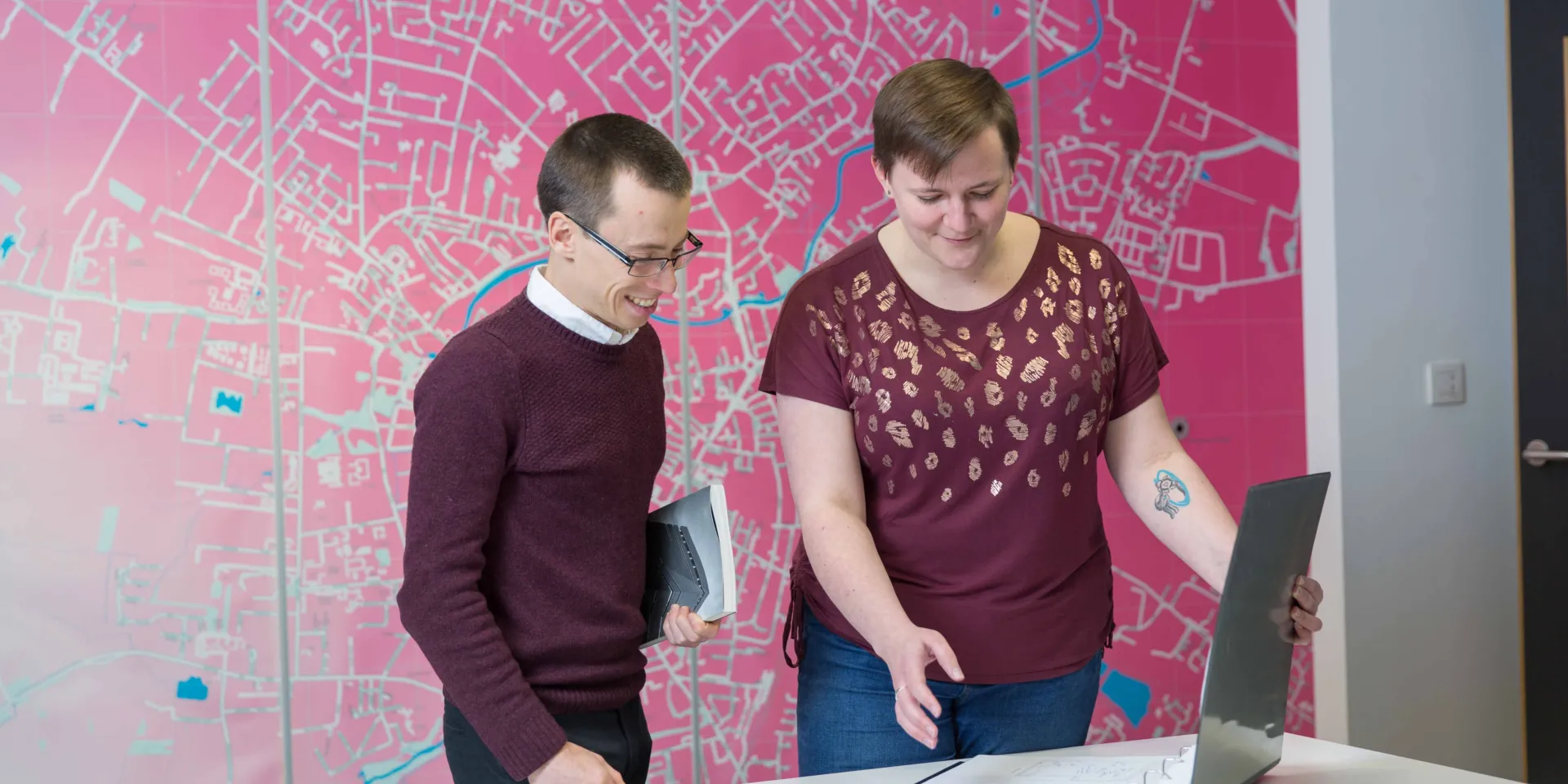 Two people looking at the architectural drawings on desk in Max Fordham Cambridge office