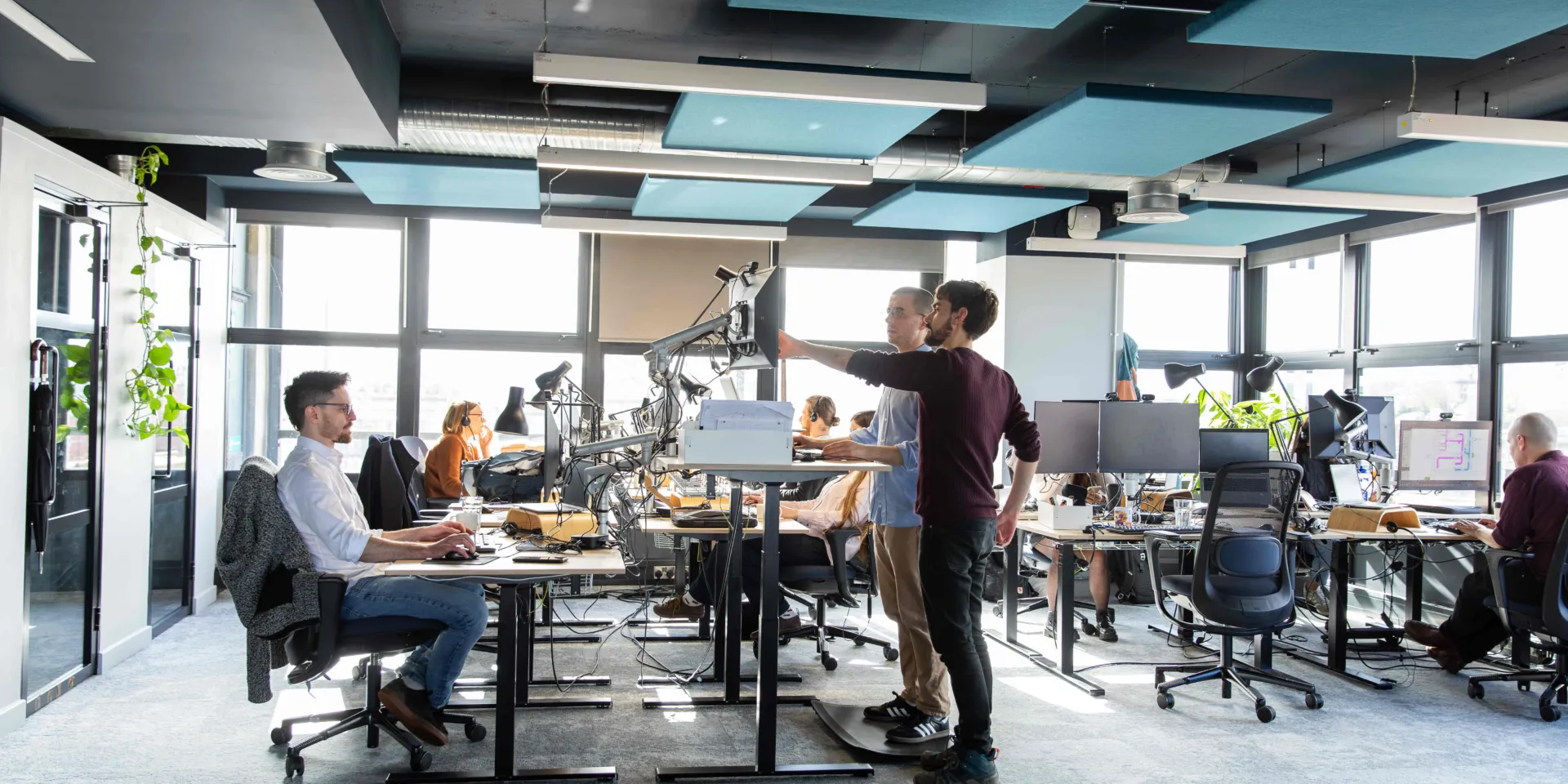 An internal photo showing Max Fordham Bristol office, some are sitting and some are using the standing desks