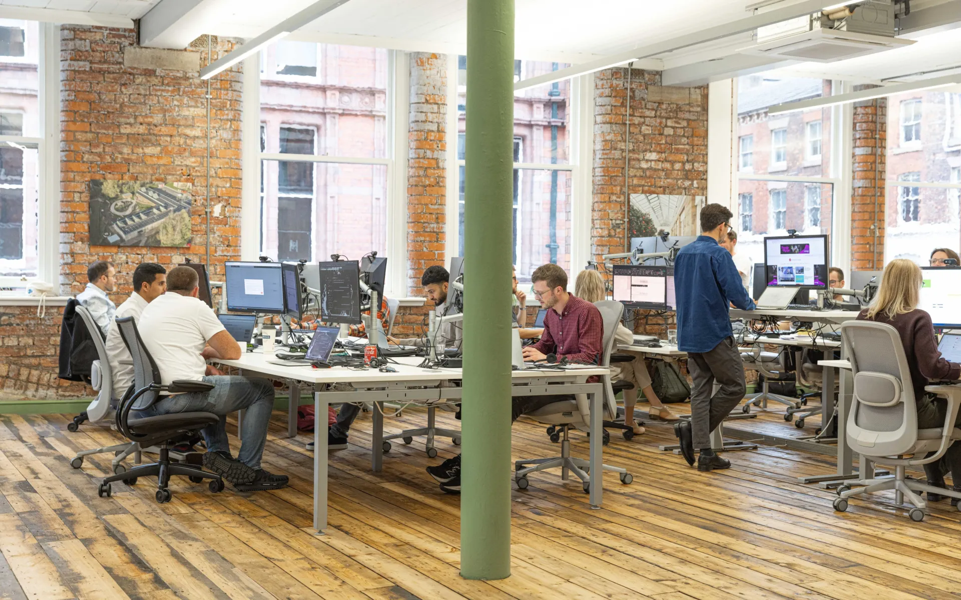 People working at desks in an open plan office with wooden floors