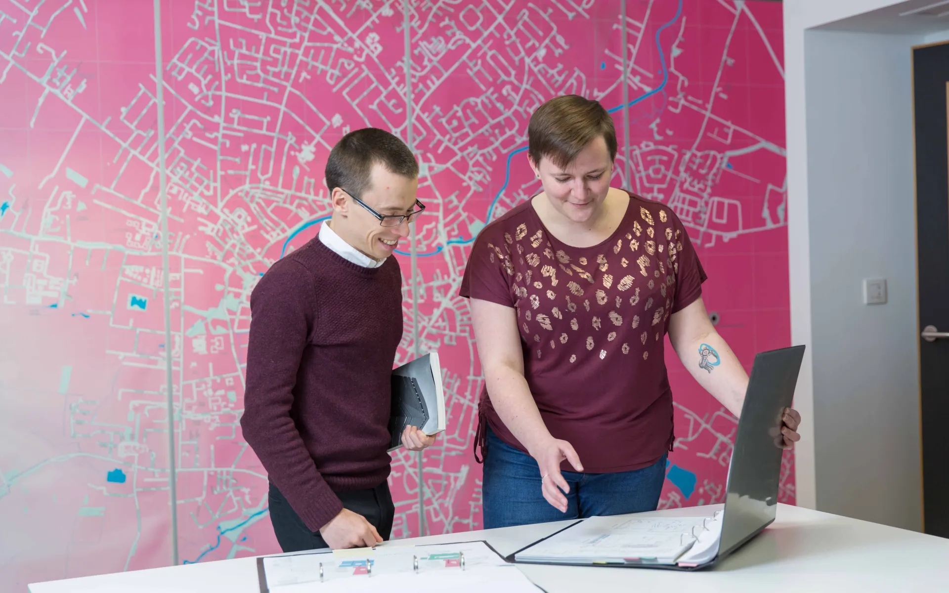 Two people looking at the architectural drawings on desk in Max Fordham Cambridge office