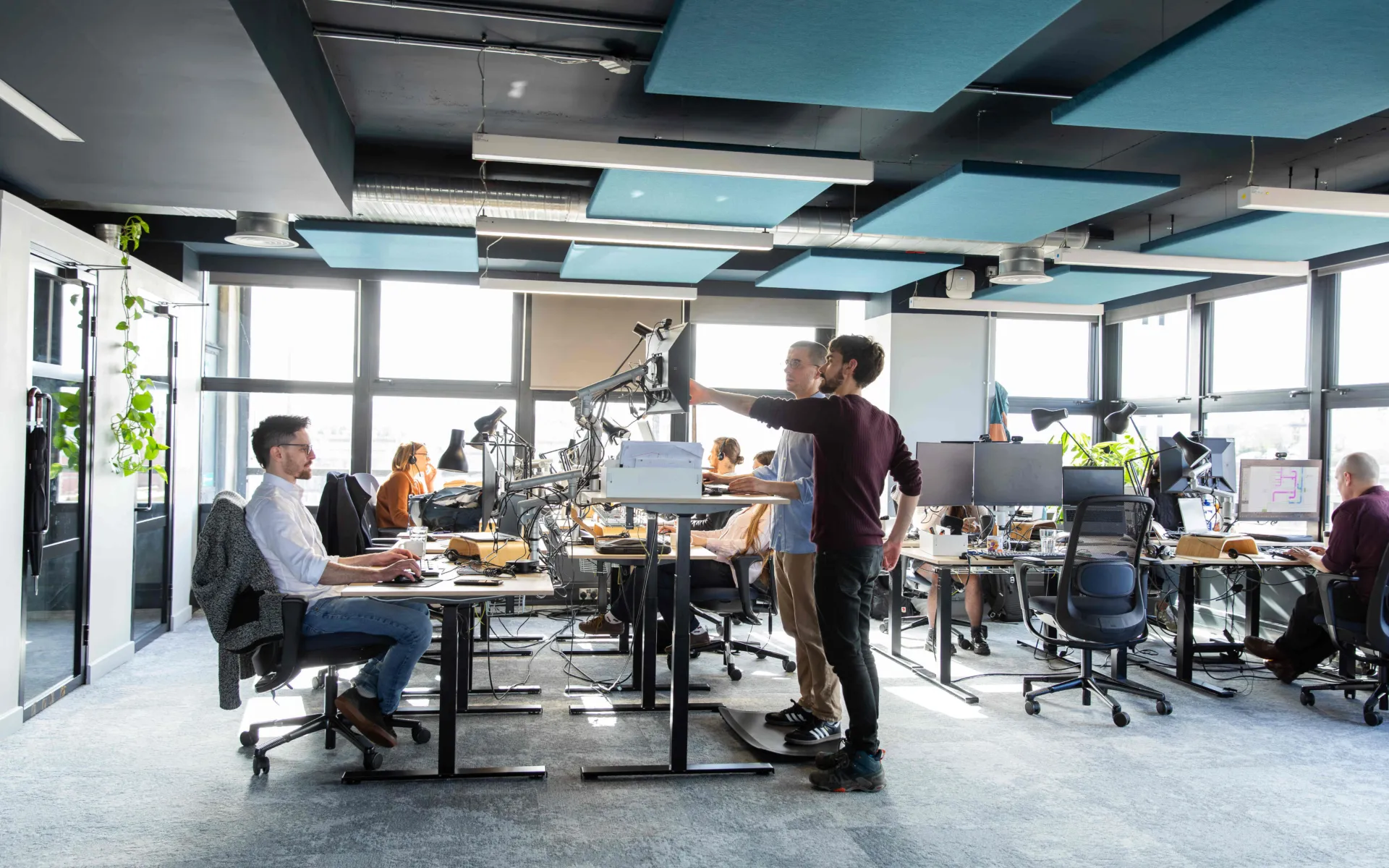 An internal photo showing Max Fordham Bristol office, some are sitting and some are using the standing desks