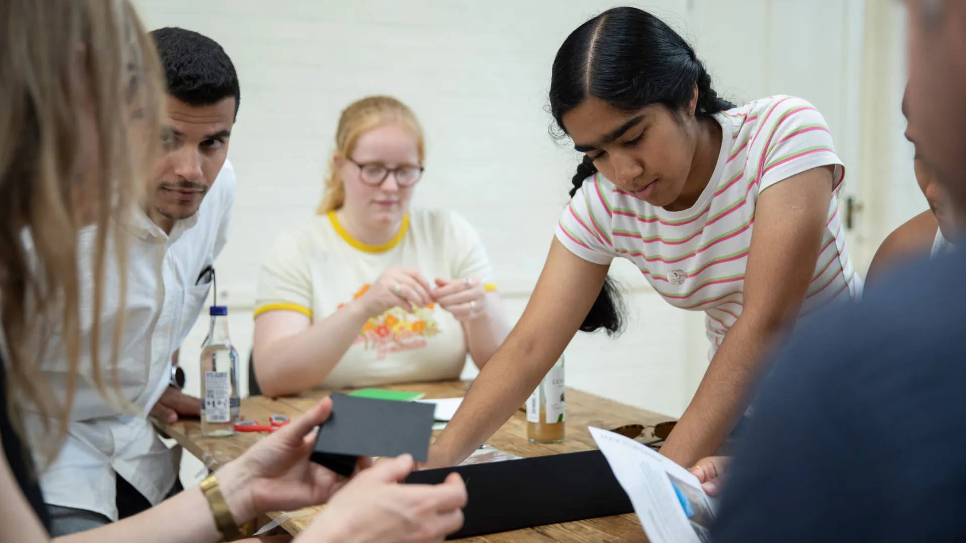 Five people working together to build a building using paper