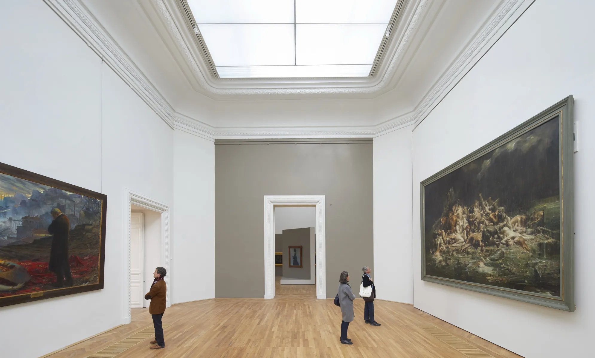 Visitors view the large artworks on the wall of the gallery