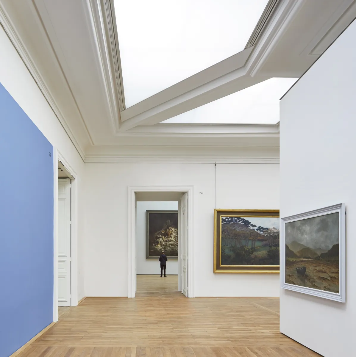 A white gallery with wooden floors and large skylights
