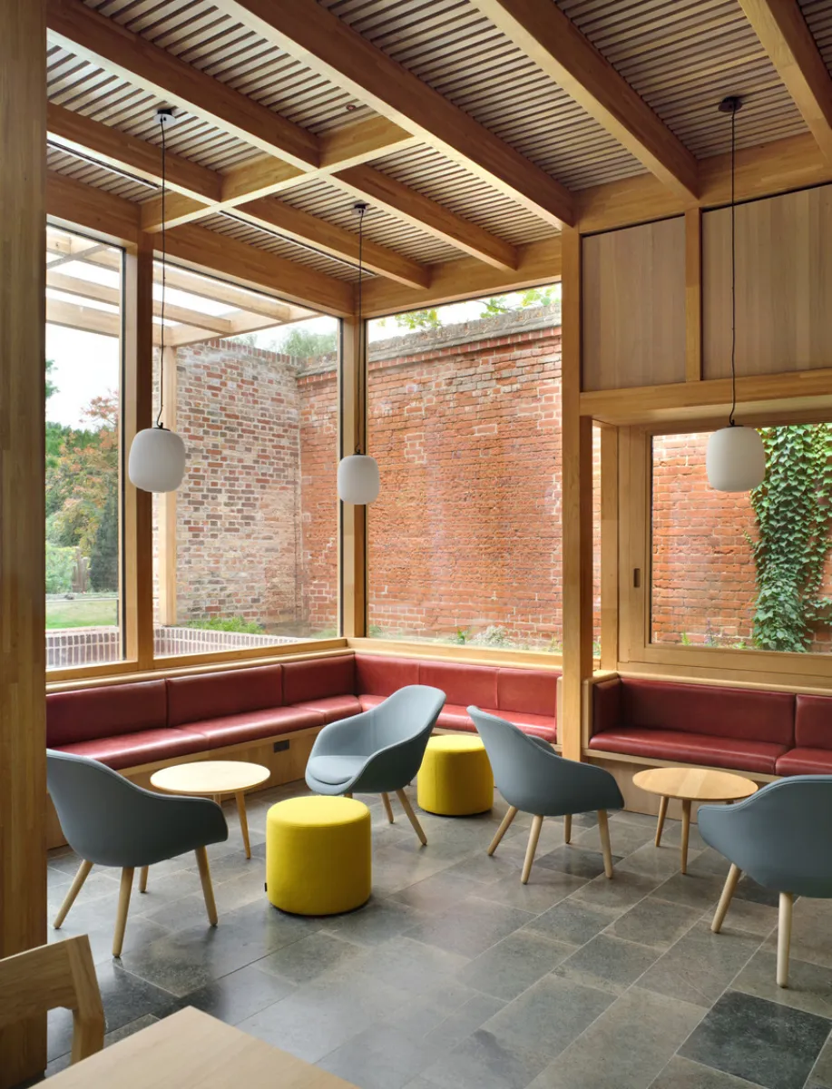 tables and chairs in a cafe with wooden beams and walls and large window