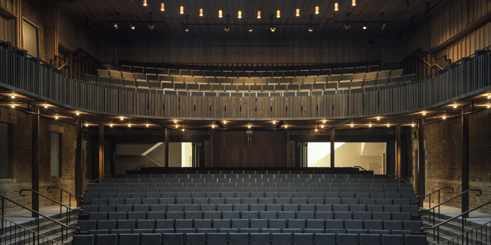 Black seating in an opera house surrounded by wooden panelling