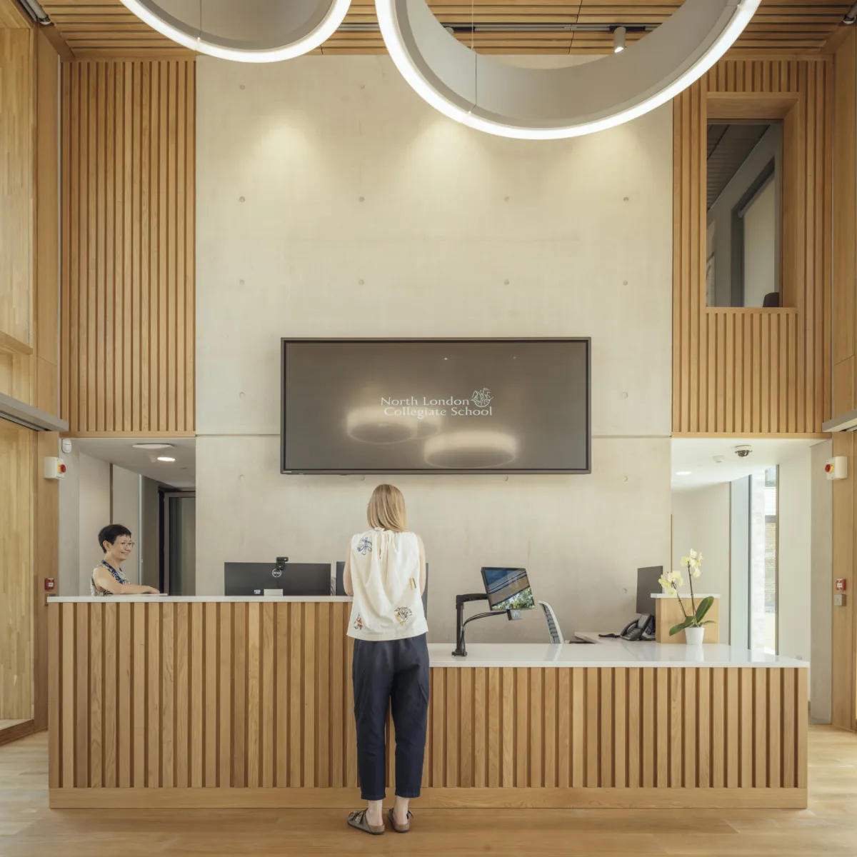 Modern wooden reception desk with people standing at it
