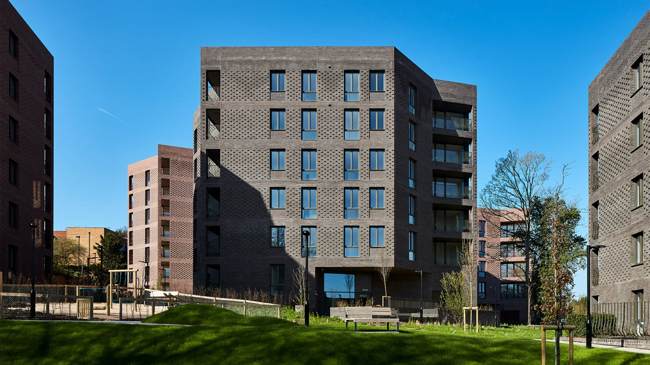 image shows a housing building with a green in front and blue skies