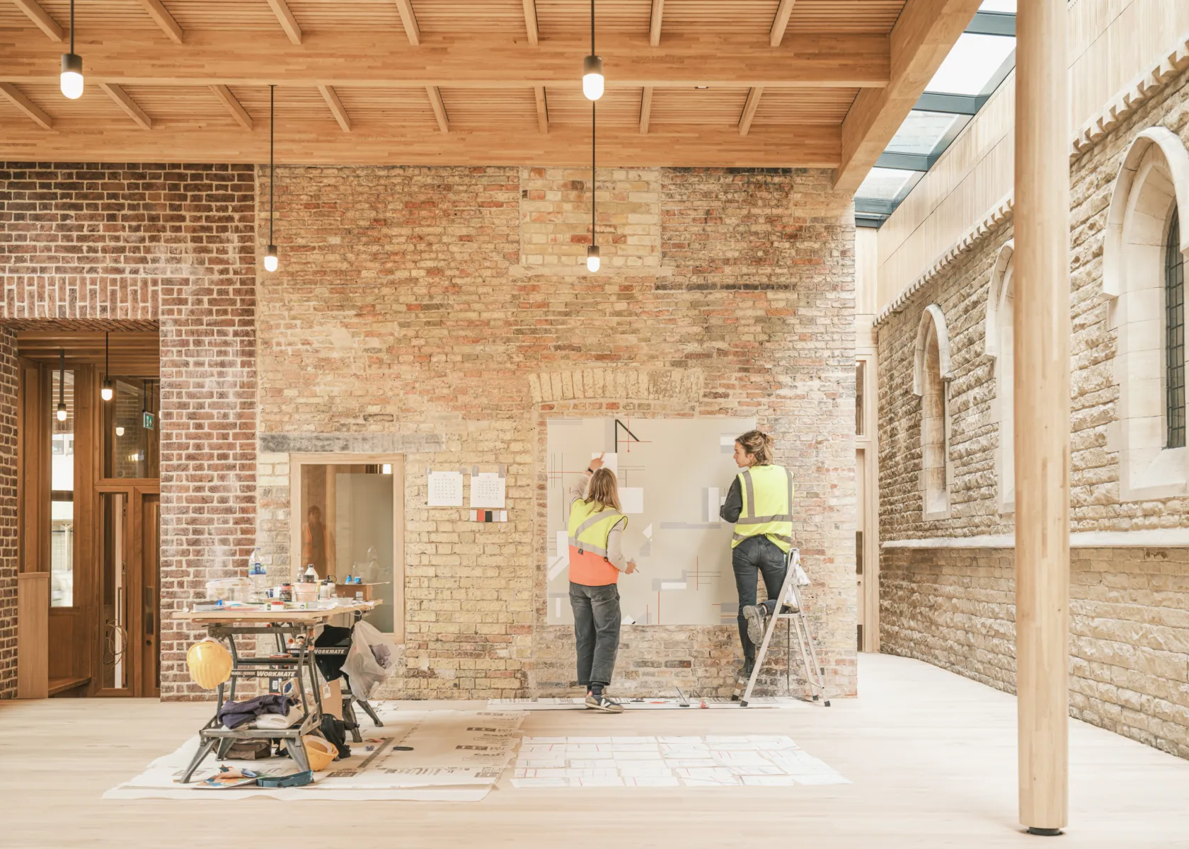 Artists painting an interior brick wall