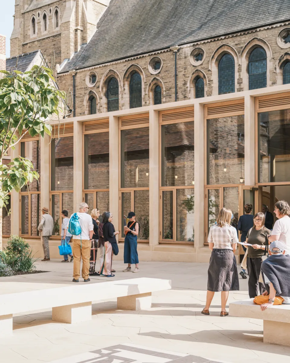 Students milling around a glass and wooden extension to a historic building