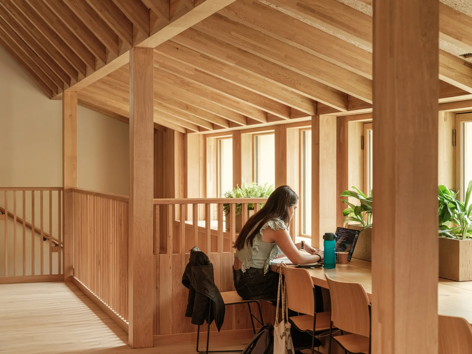 personw with ling hair studying in front of window with modern wooden ceiling