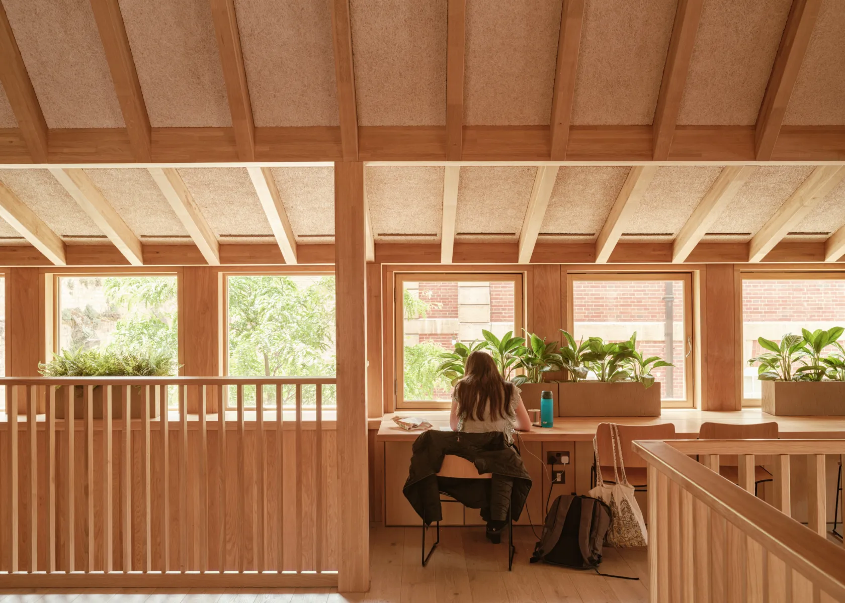 person with long hair studying in front of the window