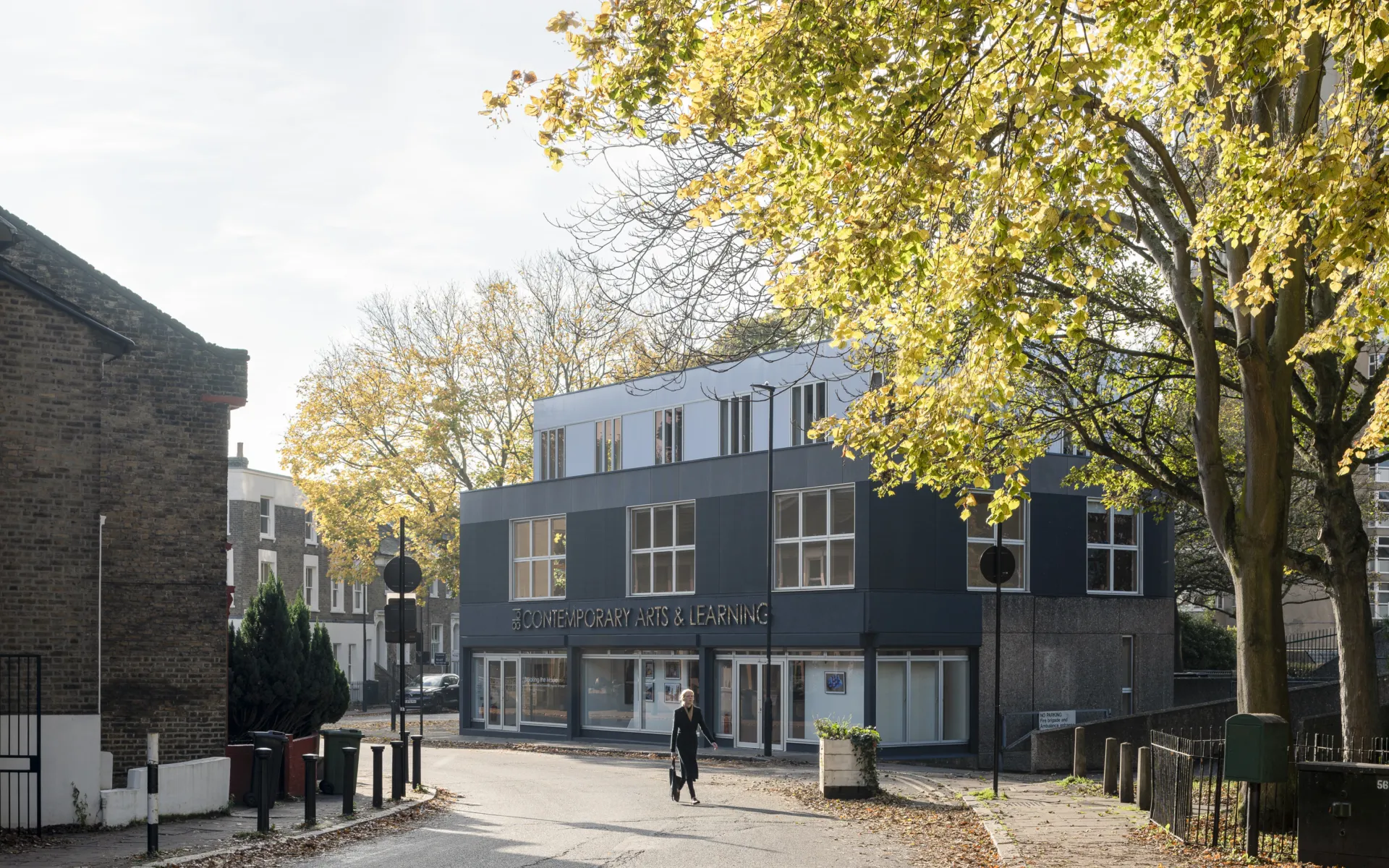 The exterior of a three storey building on an autumnal street
