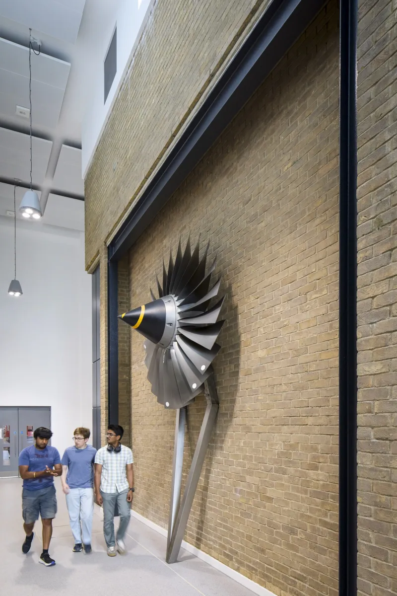 Interior corridor with a turbine sculpture mounted on a brick wall.