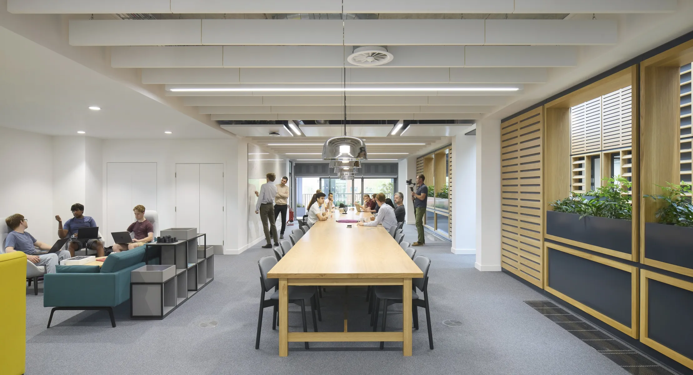 Communal workspace with a long table, seating areas and people collaborating.