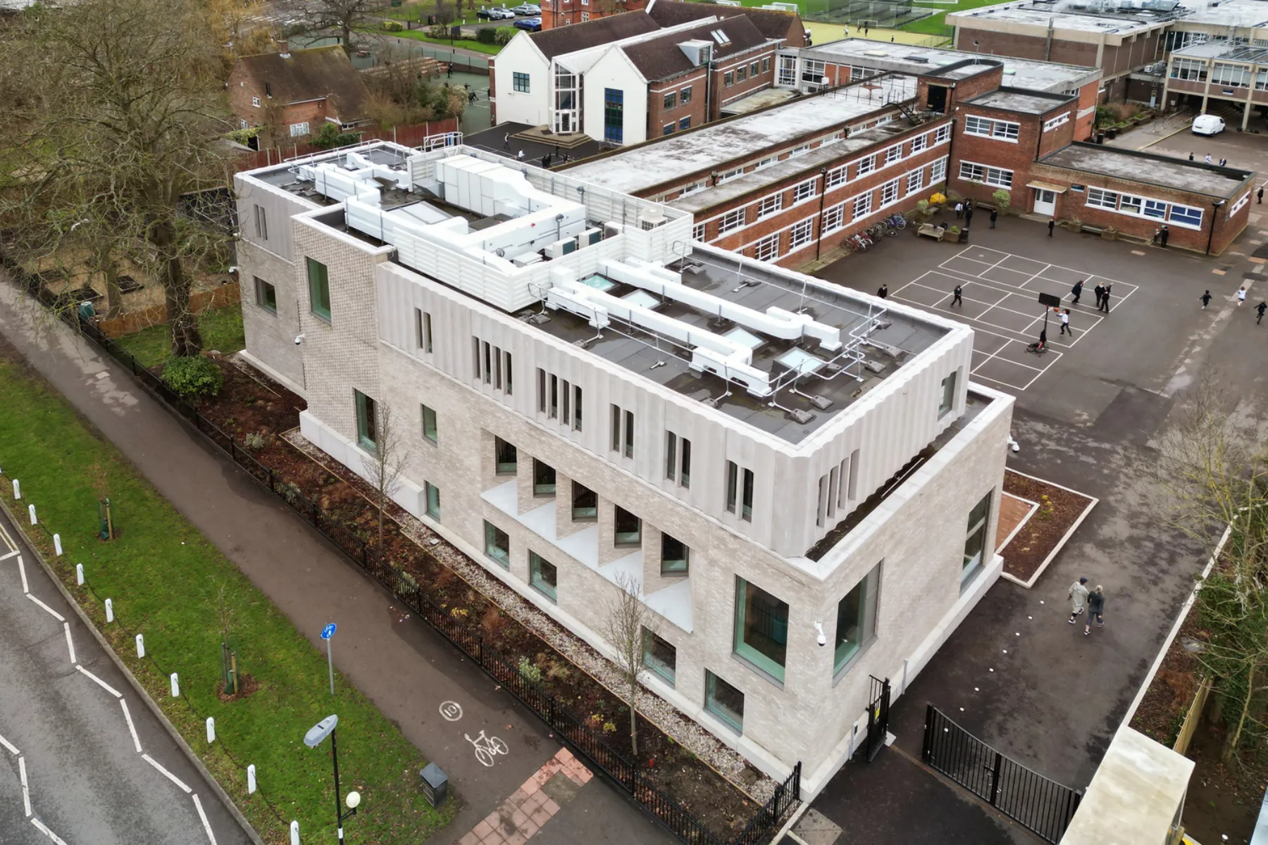 Aerial image of a light grey building on a leafy campus