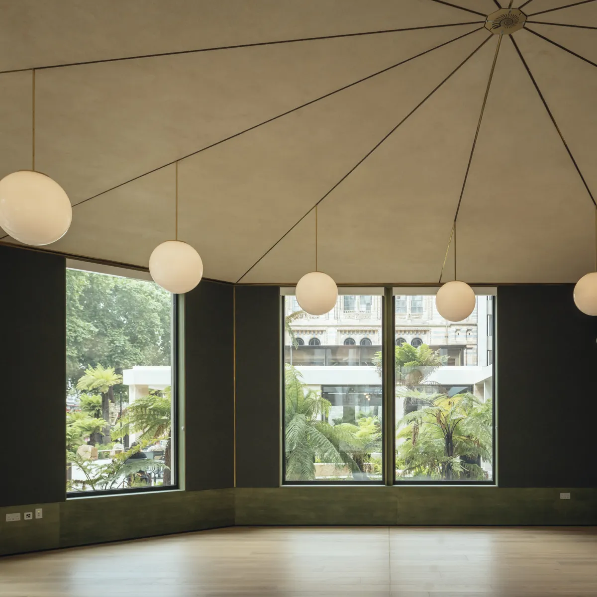 Interior shot of new event space at the Garden Room cafe, showing fan-shaped pale roof, large windows, and round pendant lights.