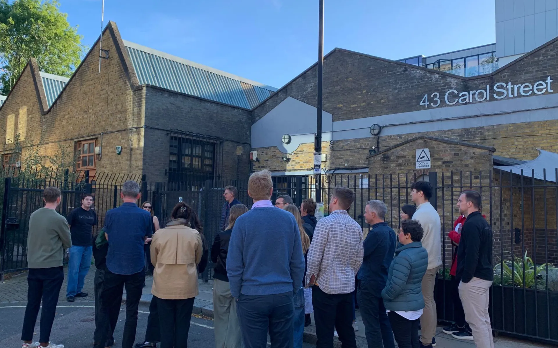 people standing in front of a brick building with a sign that says 43 Carol Street