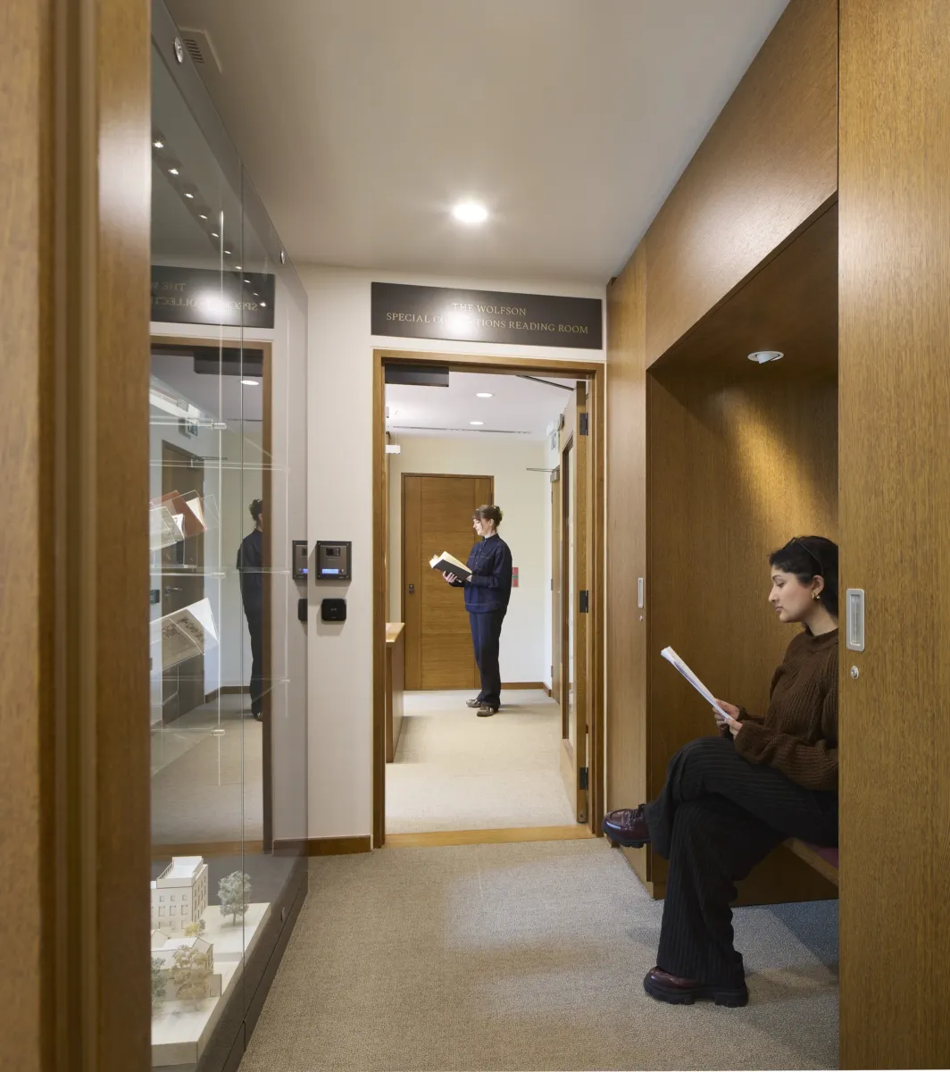 student relaxing in a corridor in front of a glass window housing artefacts