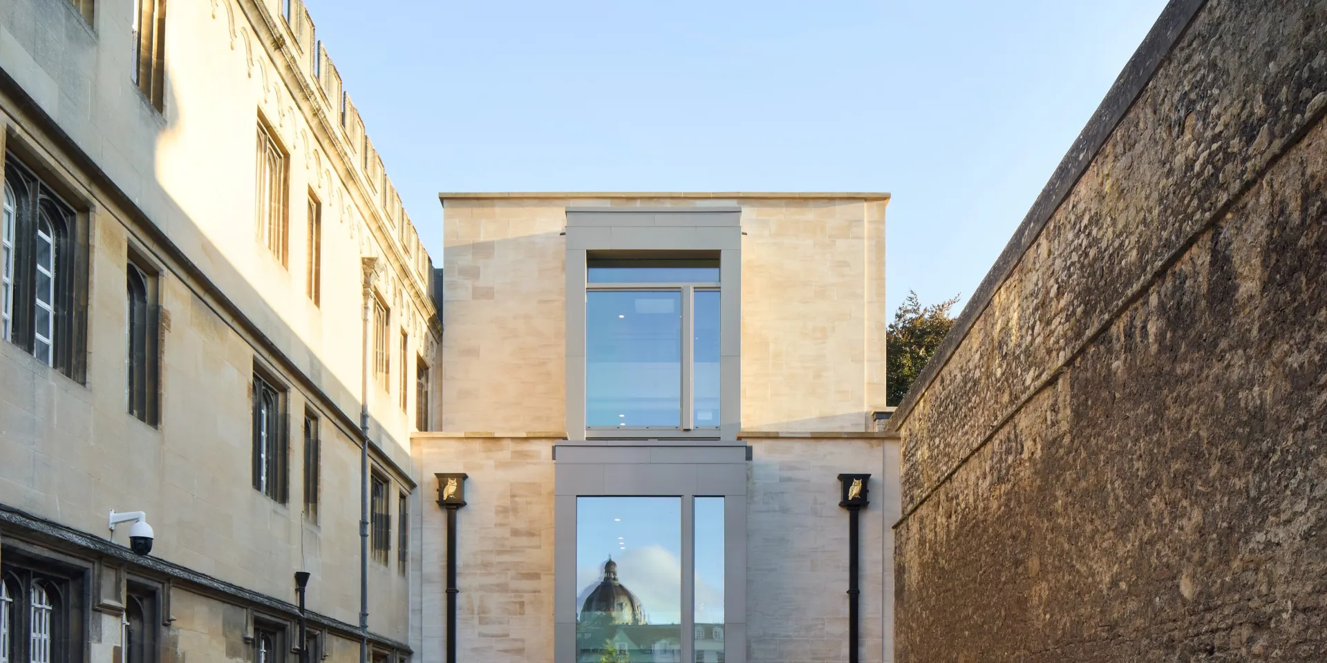 Historic city wall and a historic building facade flank a new building facade at the centre