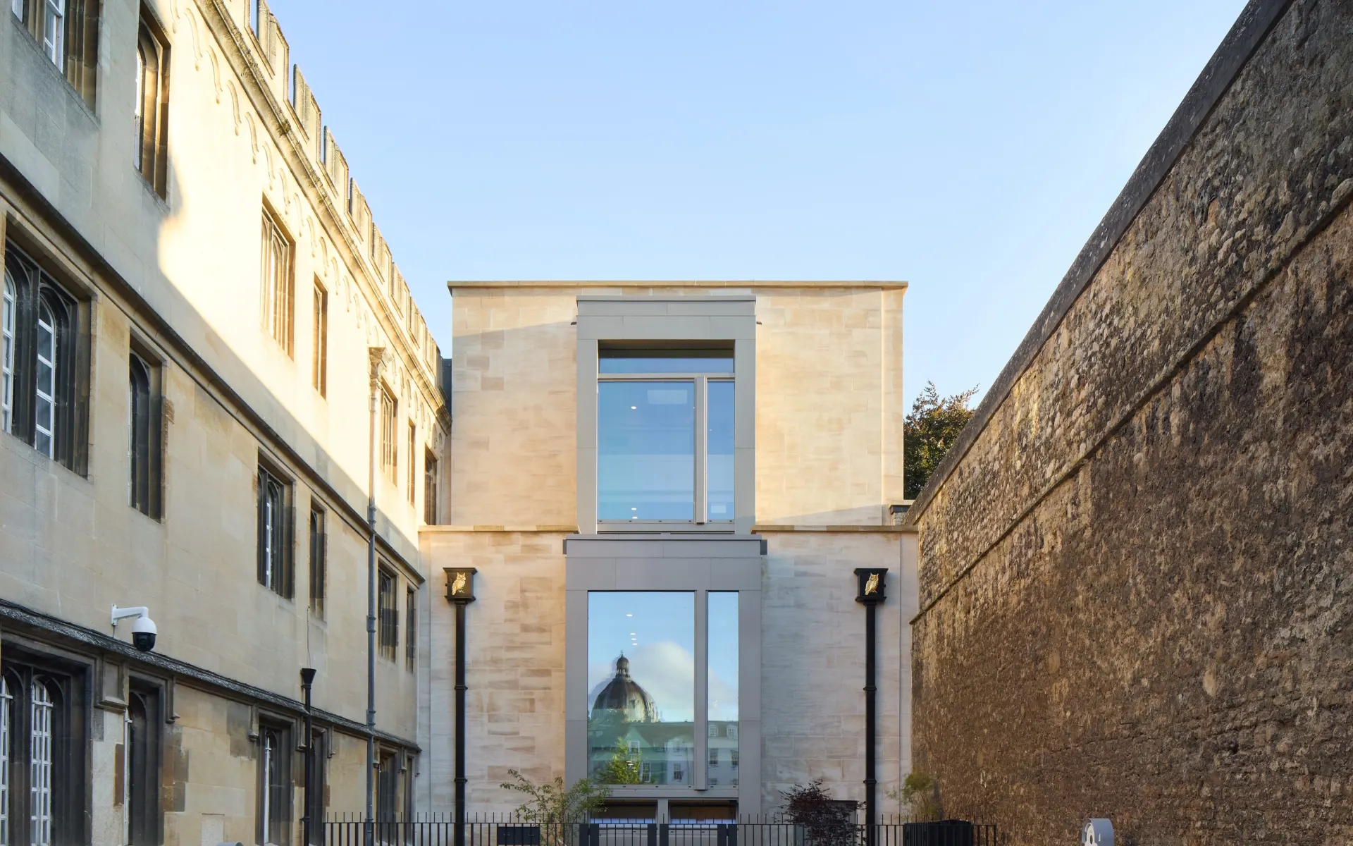 Historic city wall and a historic building facade flank a new building facade at the centre