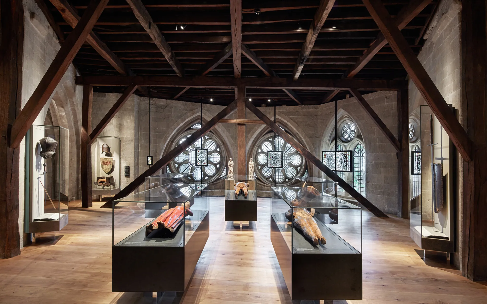 Exhibits in a historic space with wooden ceiling beams and Abbey windows