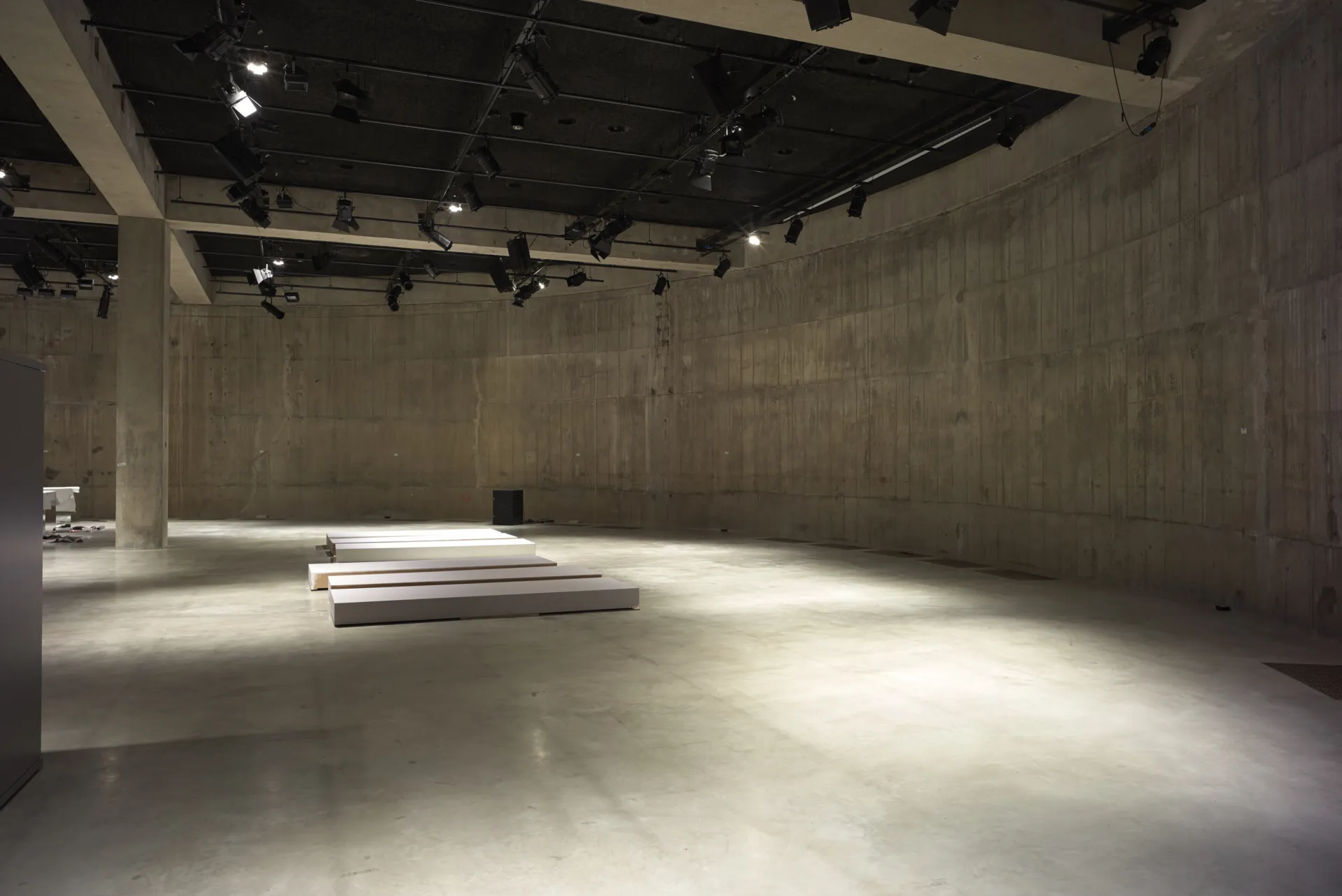 The interior of an empty concrete building, lit with spot lights