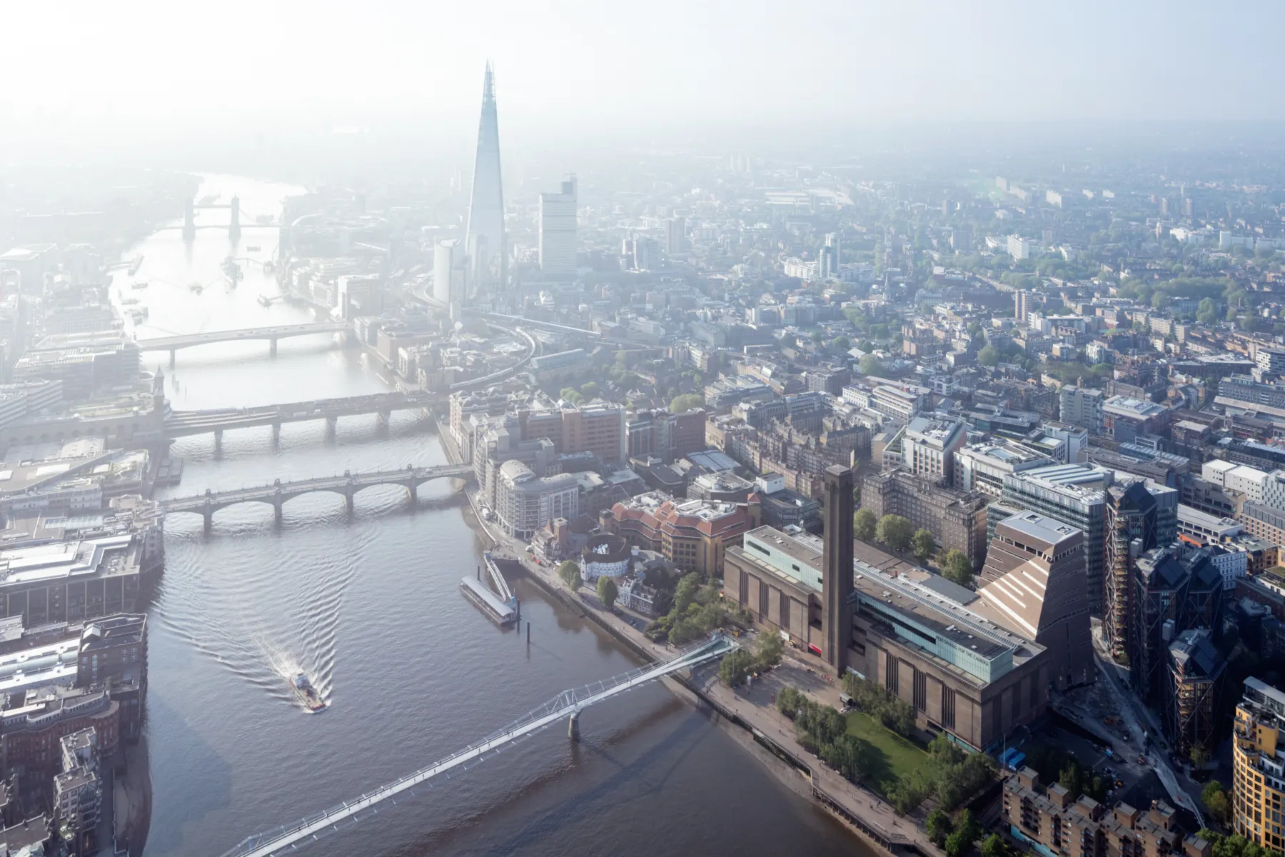 An aerial photograph of London and the Thames looking east, showing the Millennium Bridge, Southwark Bridge, London Bridge, and Tower Bridge, with the Shard and Tate Modern at Bankside visible