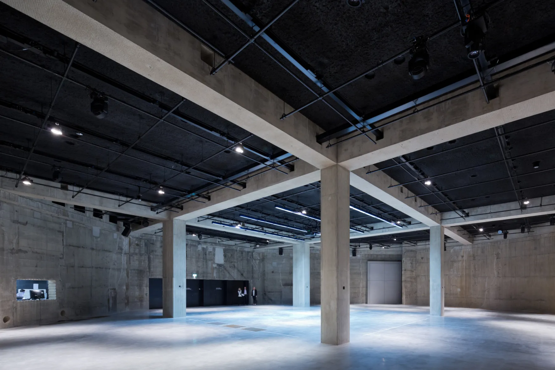 A large empty concrete space, lit artificially with spot lights in the ceiling