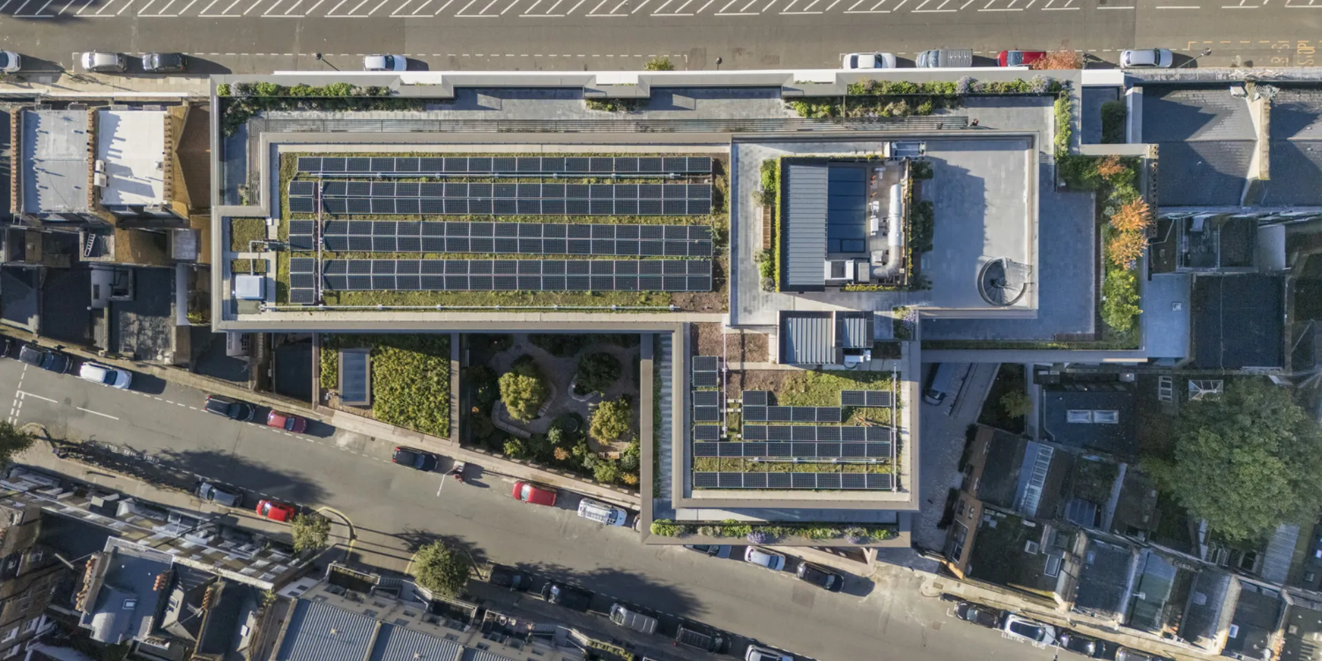 aerial shot of a building, seeing PV panels and greens on the roof